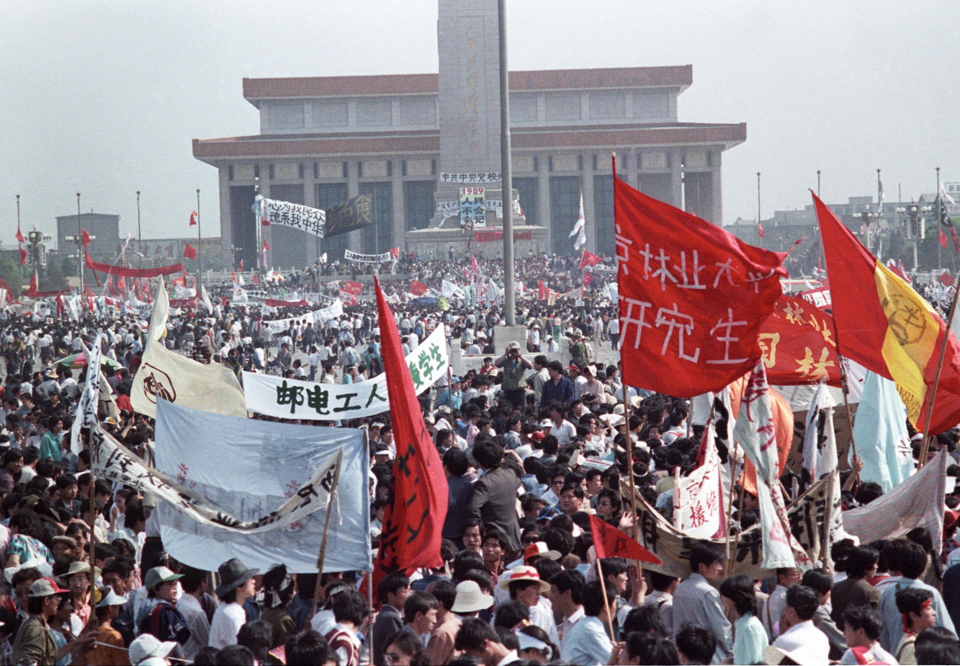 Crowds protest in Tiananmen Square carrying banners written in Chinese.