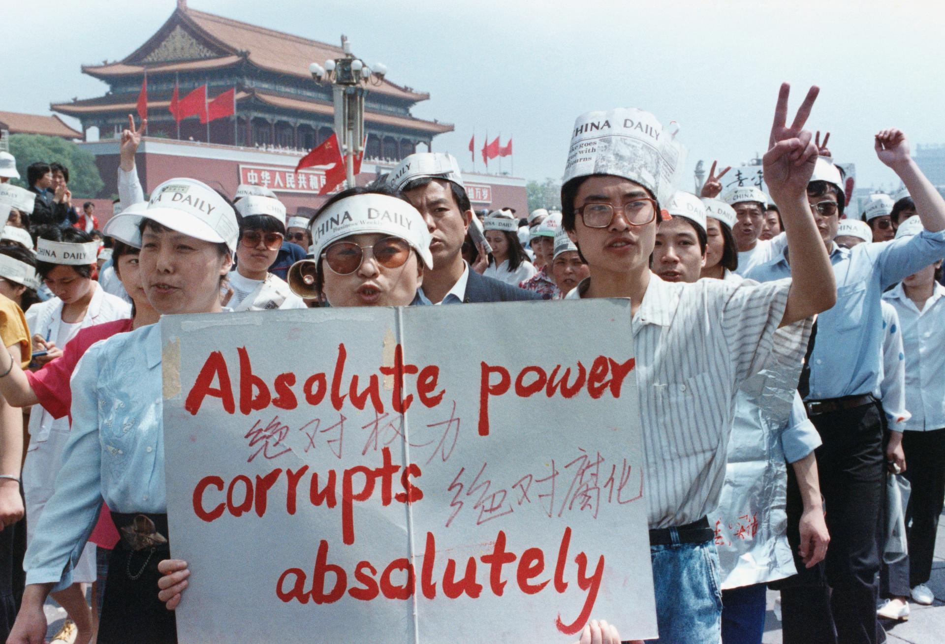Protesters in Tiananmen Square hold up a sign that says absolute power corrupts absolutely. 