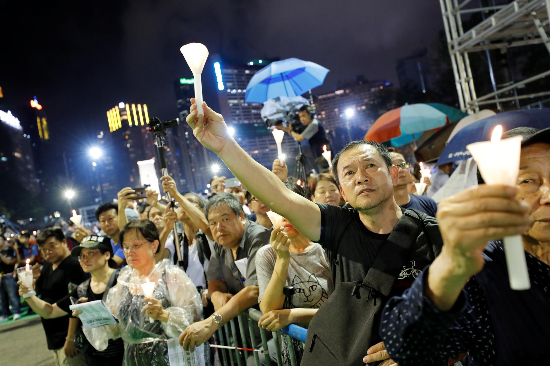 A crowd of activists holds candles in Hong Kong at night. 