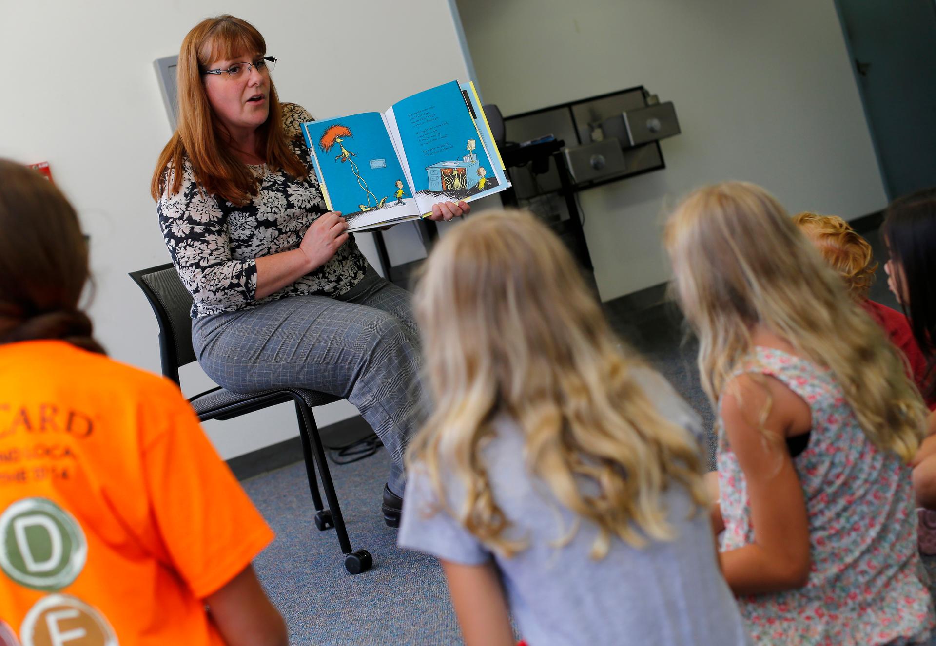 a teacher reads a book to a group of student. 