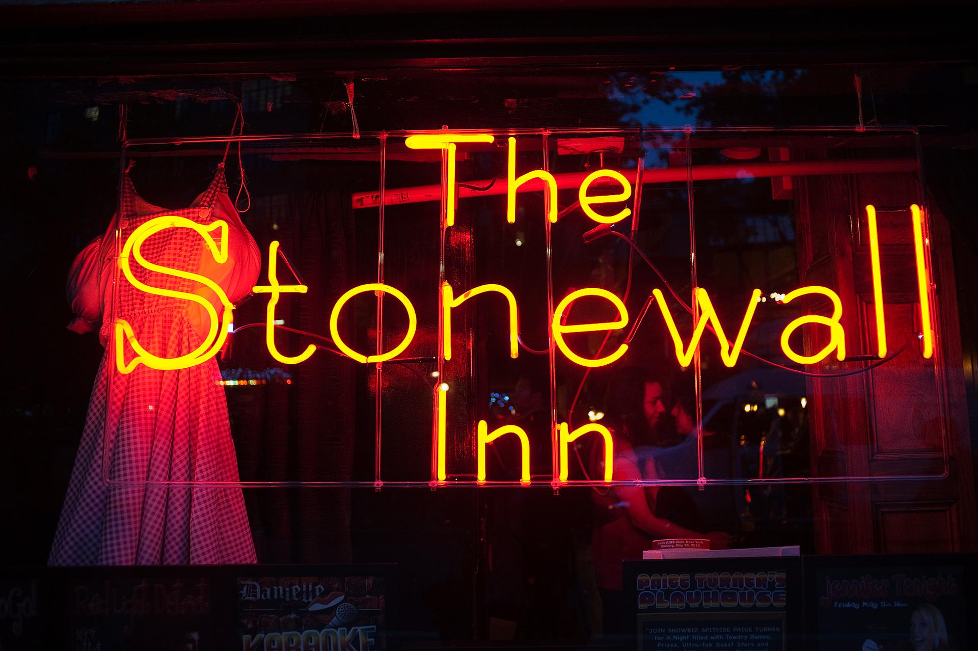 A neon sign saying "The Stonewall Inn" shines out a window.