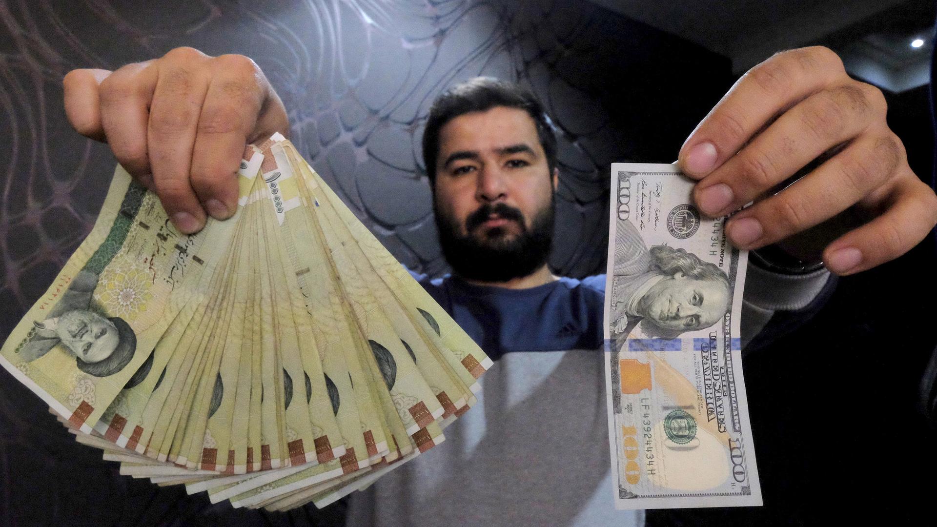 A man holds Iranian and American currency 
