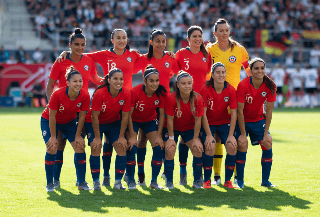 Women's soccer team posing for group shot in red uniforms. 