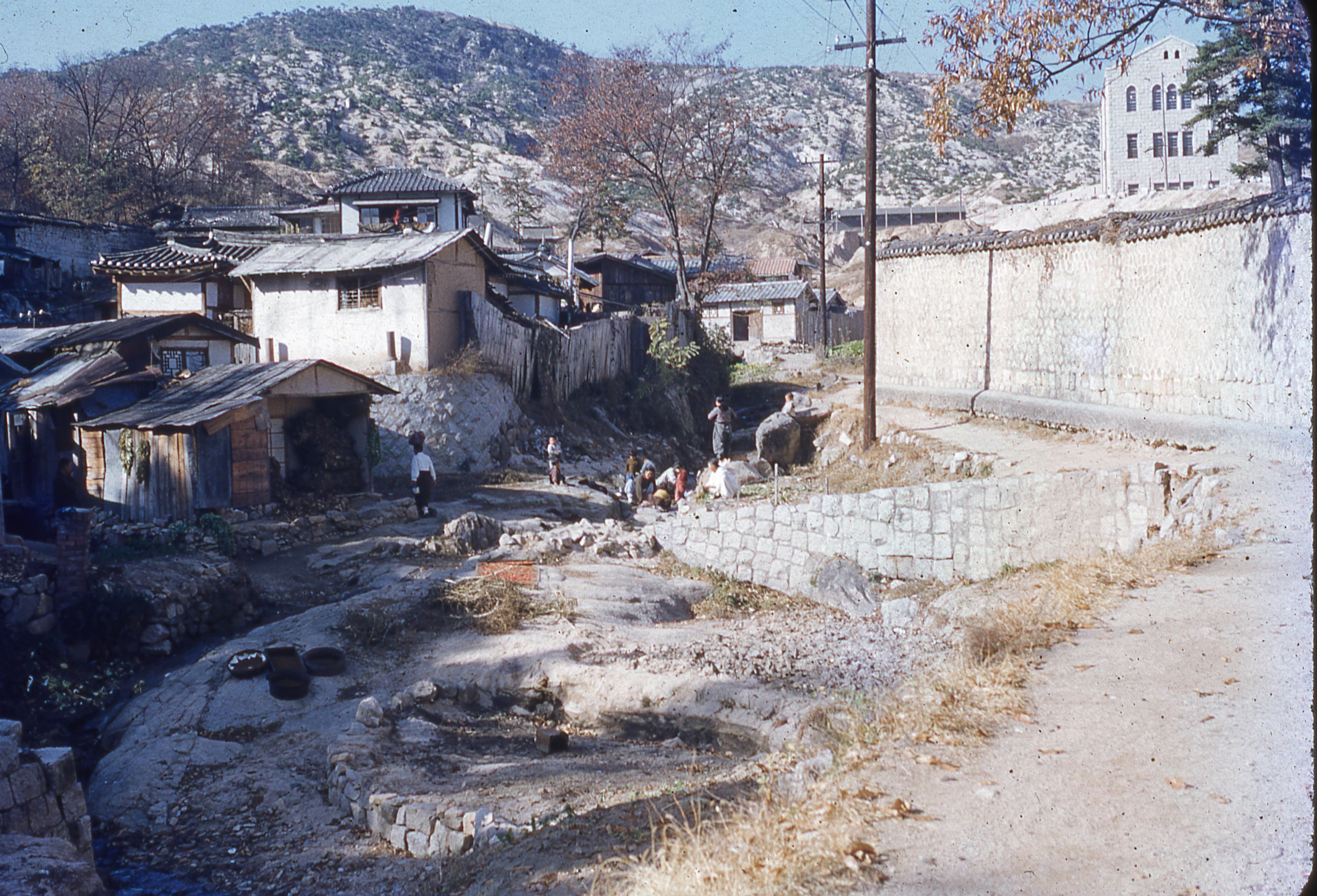 washing clothes in a stream near huts