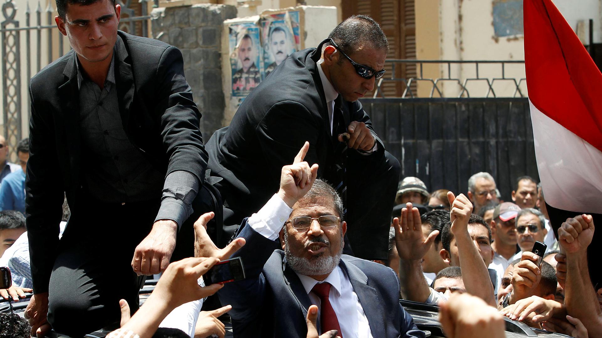 Mohammed Morsi, former president of Egypt, waved to his supporters after casting his vote at a polling station in a school in Al-Sharqya, 37 miles northeast of Cairo, on June 16, 2012.