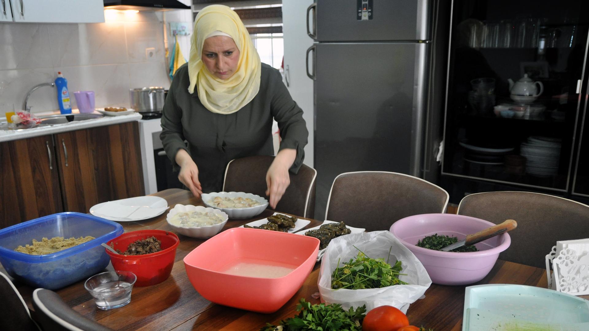 A woman stands over a spread of dishes in the kitchen 