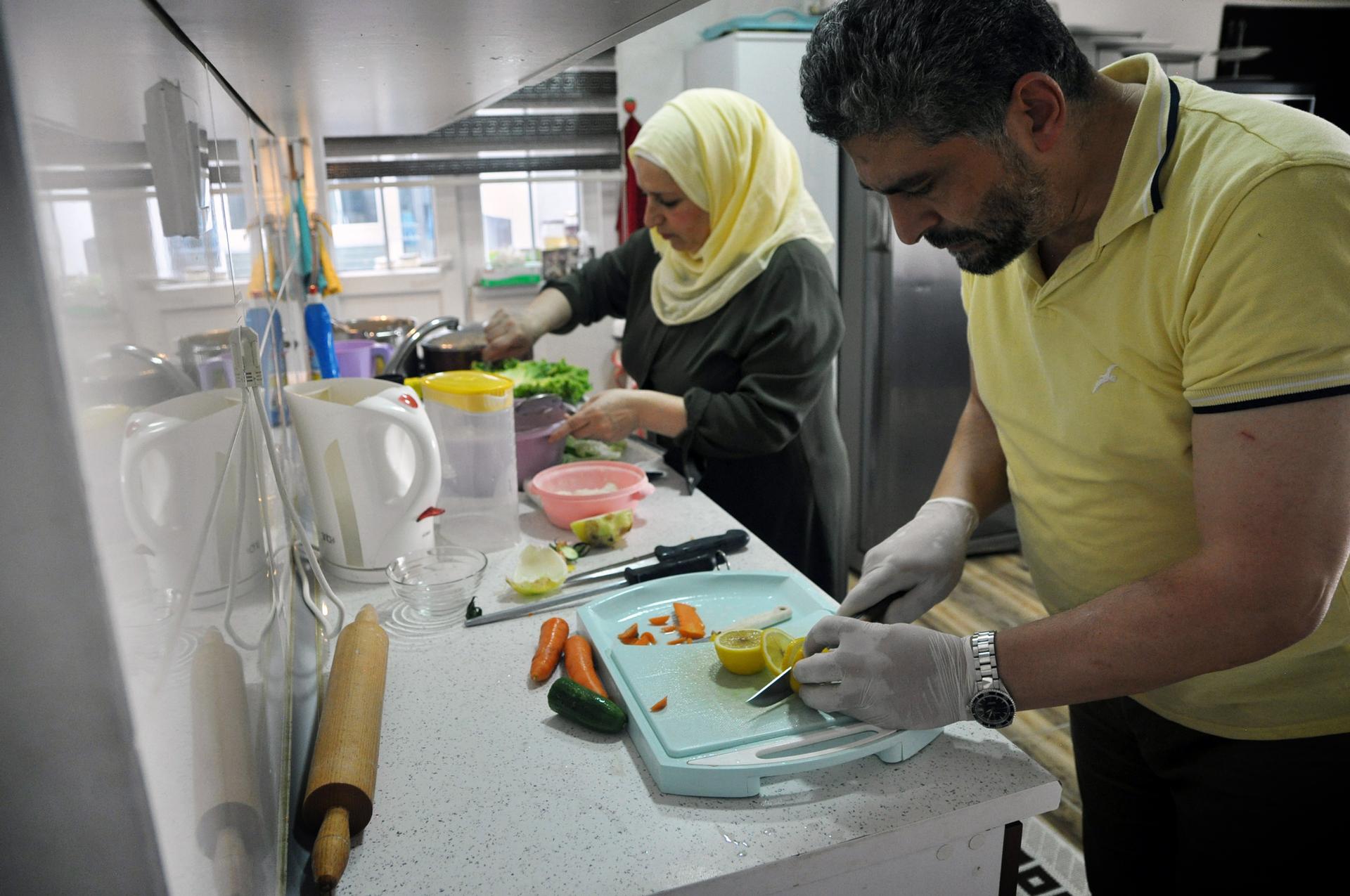 A man and woman prepare food together in a kitchen