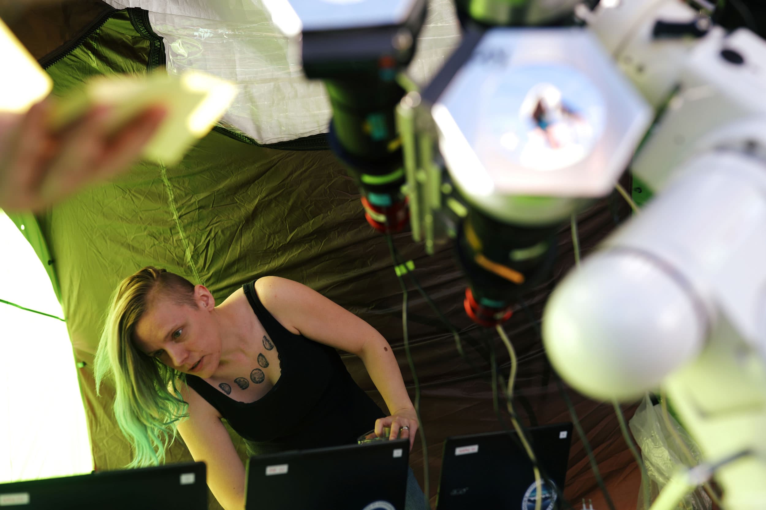 A woman is shown with blonde and blue hair looking down at computer monitors.