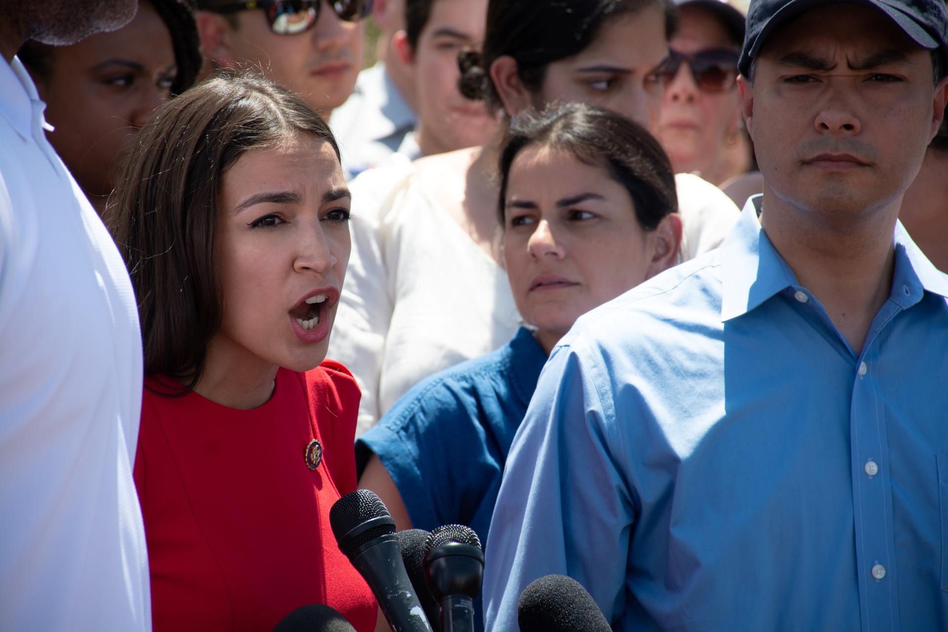 U.S. Representative Alexandria Ocasio-Cortez, standing near Rep. Joaquin Castro, speaks to the news media after she and other members of Congress toured two Border patrol stations.