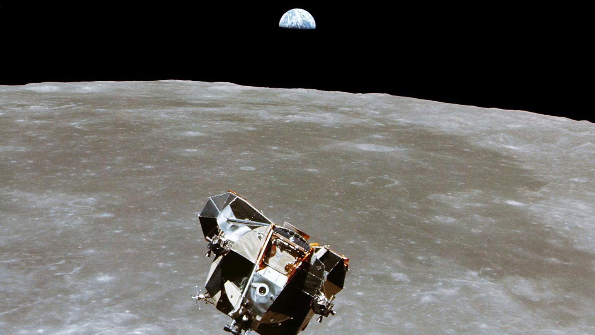 The Apollo 11 Lunar Module is shown in the nearground with the moon's surface below it and Earth shown in the distance.