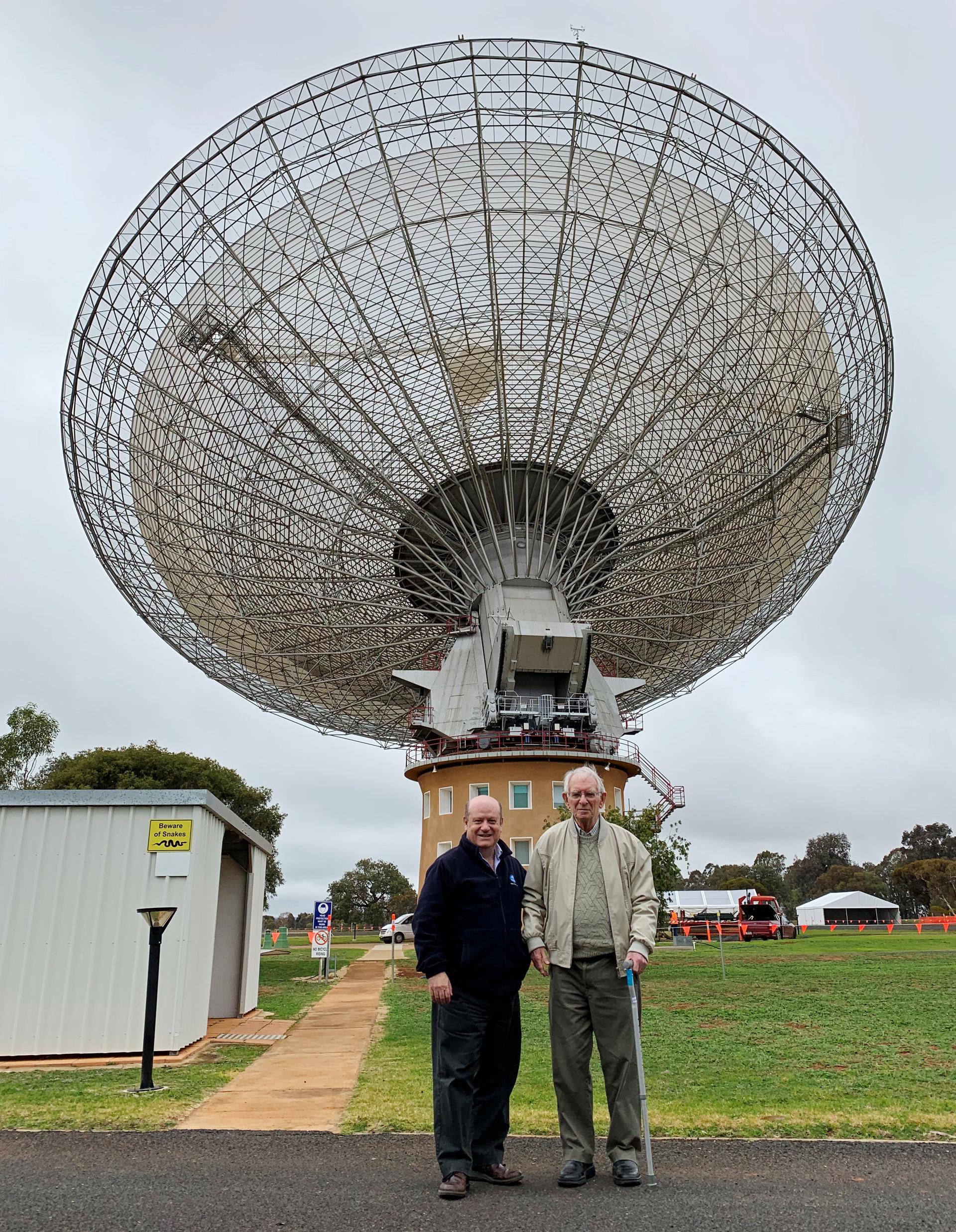 two men stand in front of an observatory