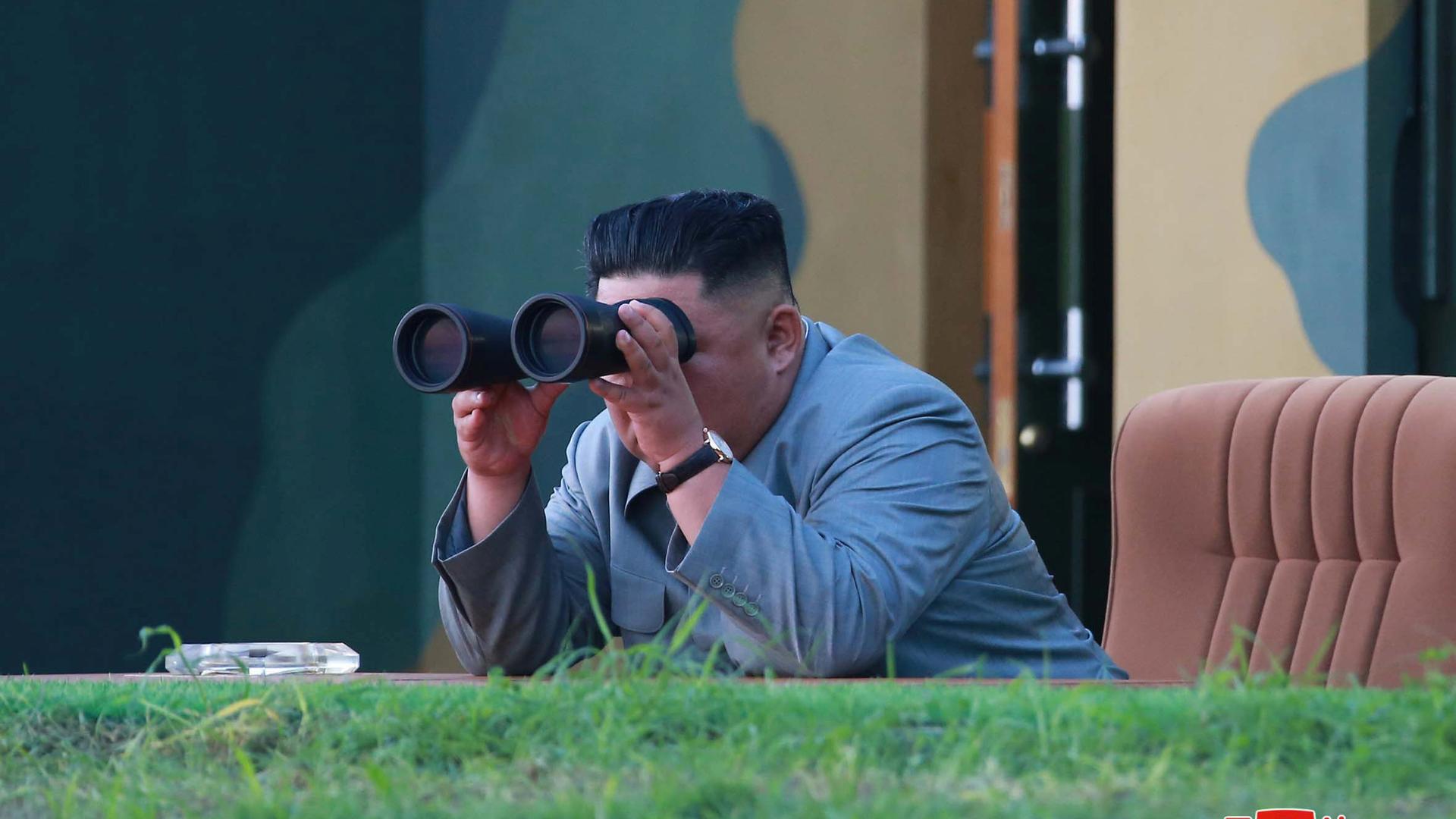 north korean leader Kim Jung-un peers through binoculars