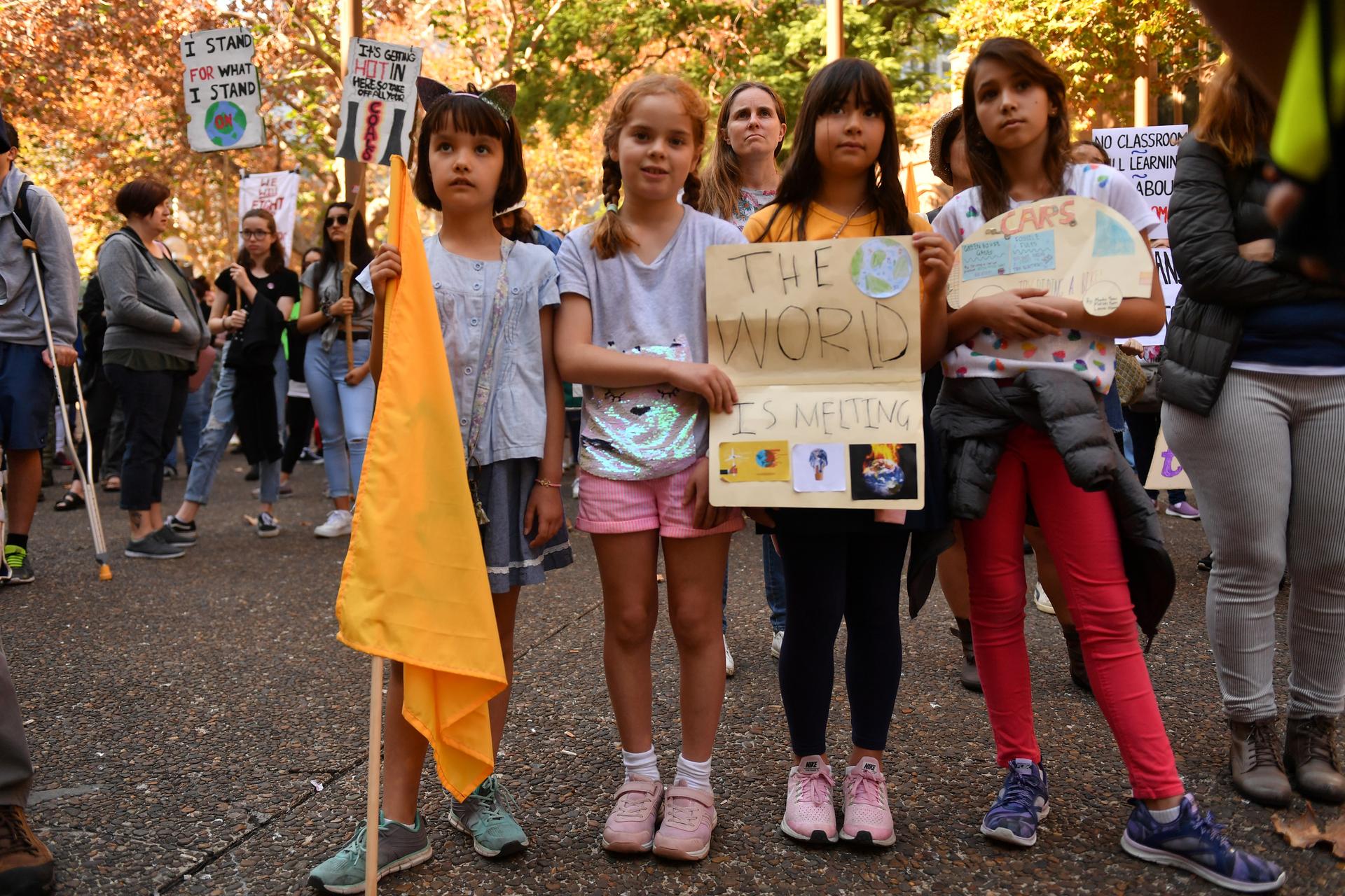 Children hold up signs protesting climate change. 