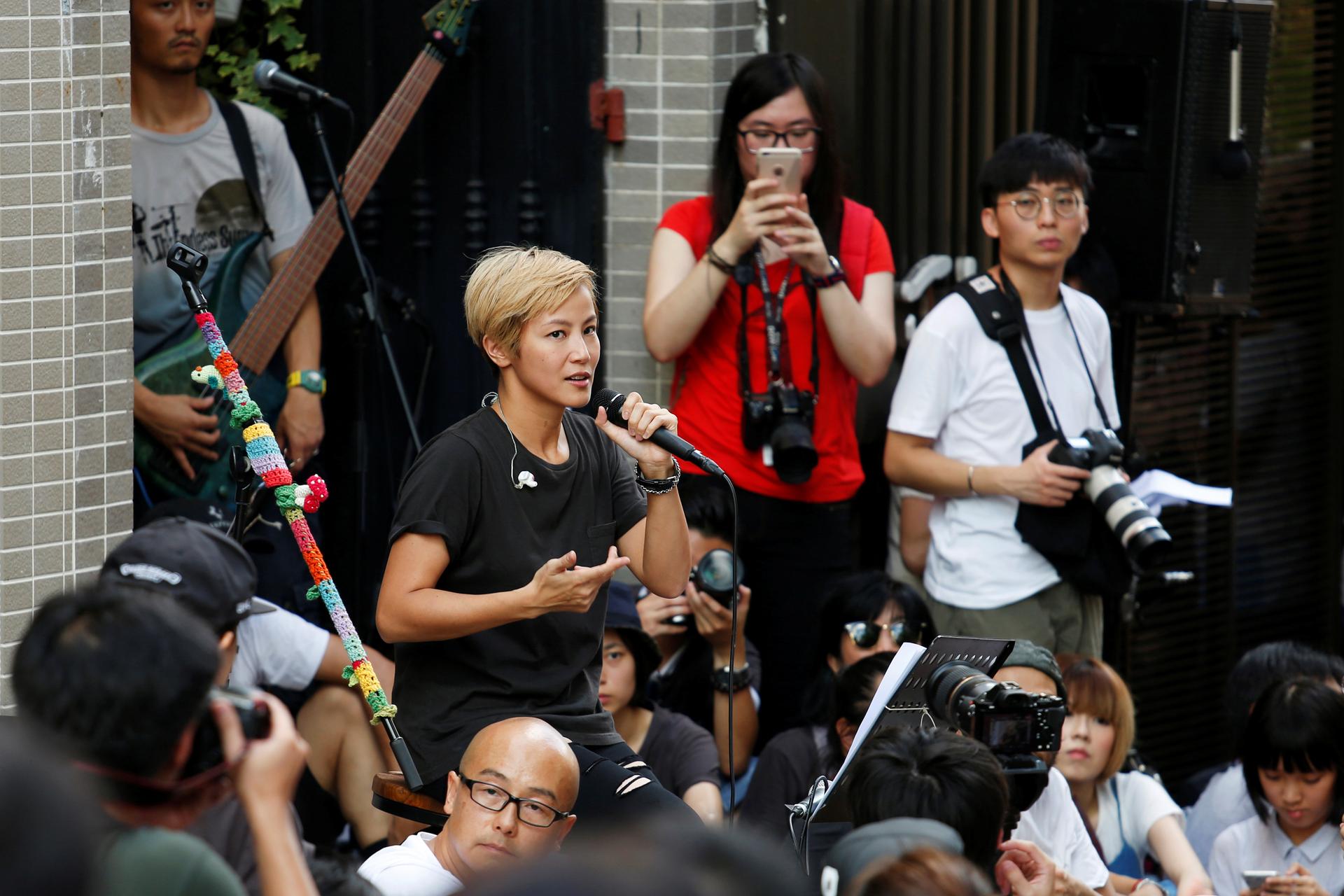 A woman holds a microphone in a crowd.
