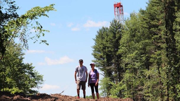 Kenton Ganster, left, stands with his mother, Kathleen, with a drilling rig used for fracking visible in the background off of the Rachel Carson Trail north of Pittsburgh.