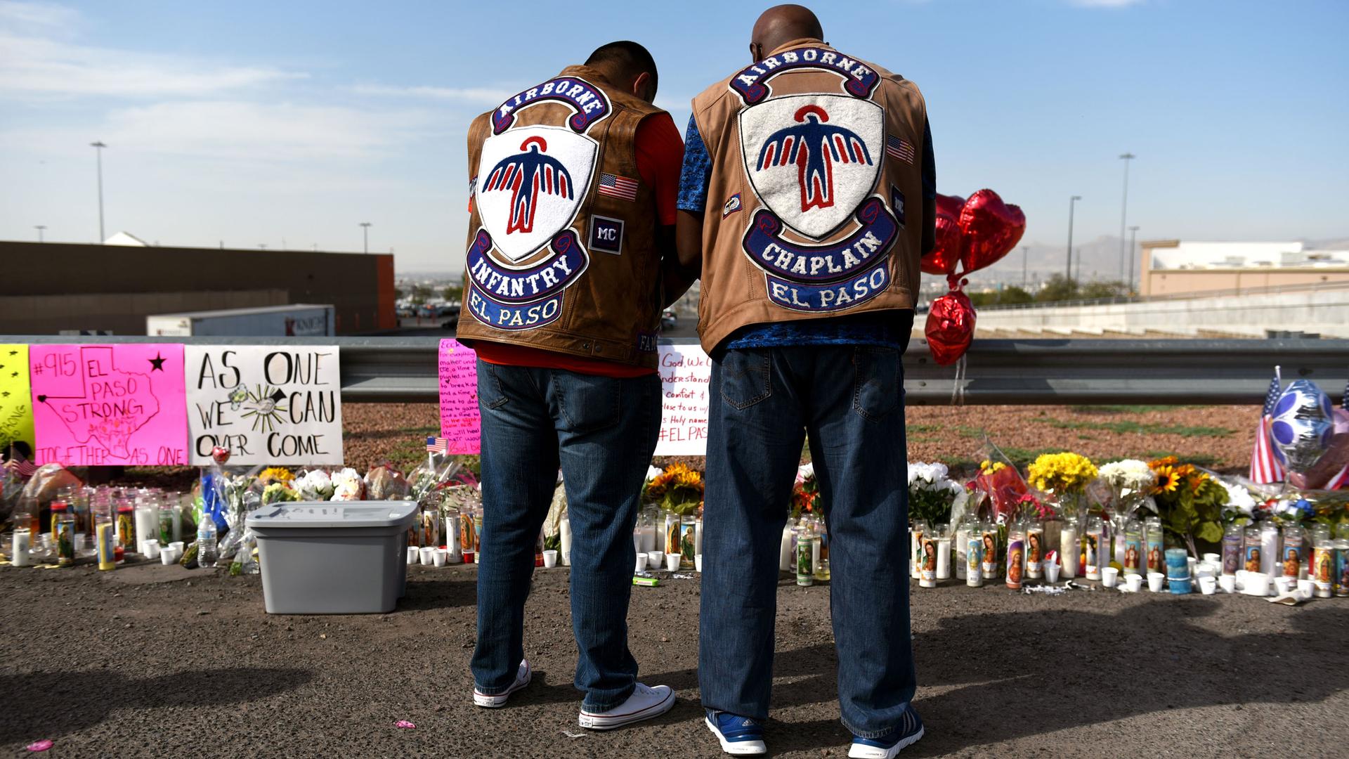 Two men bow their heads as they stand in front of an impromptu memorial for El Paso shooting victims