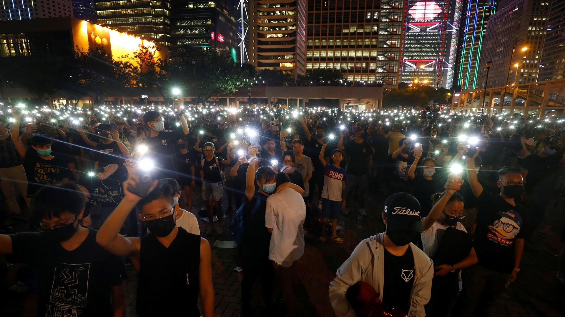 Crowds gather at night in a plaza in Hong Kong.
