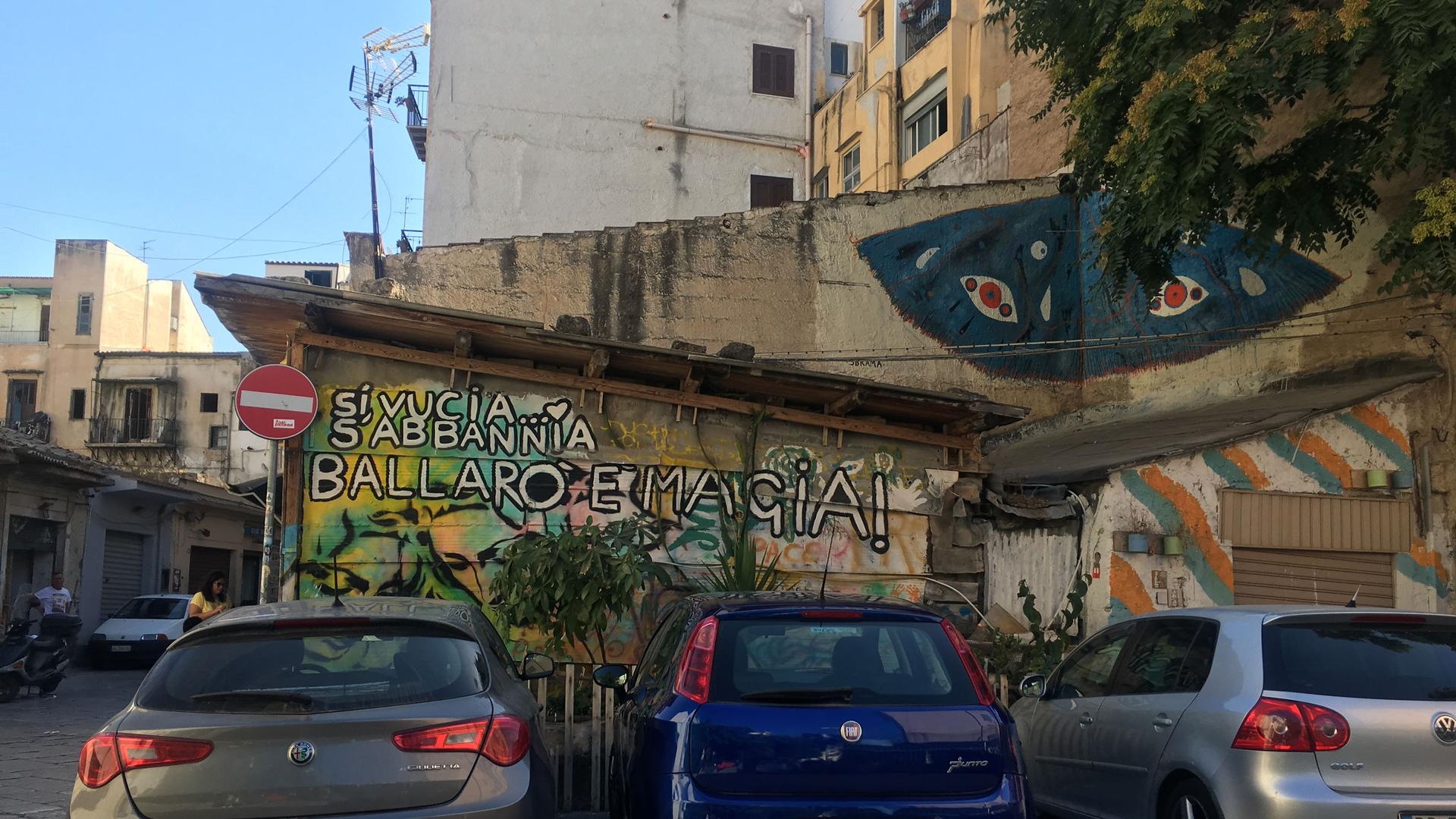 three cars are parked in front of a wall with graffiti