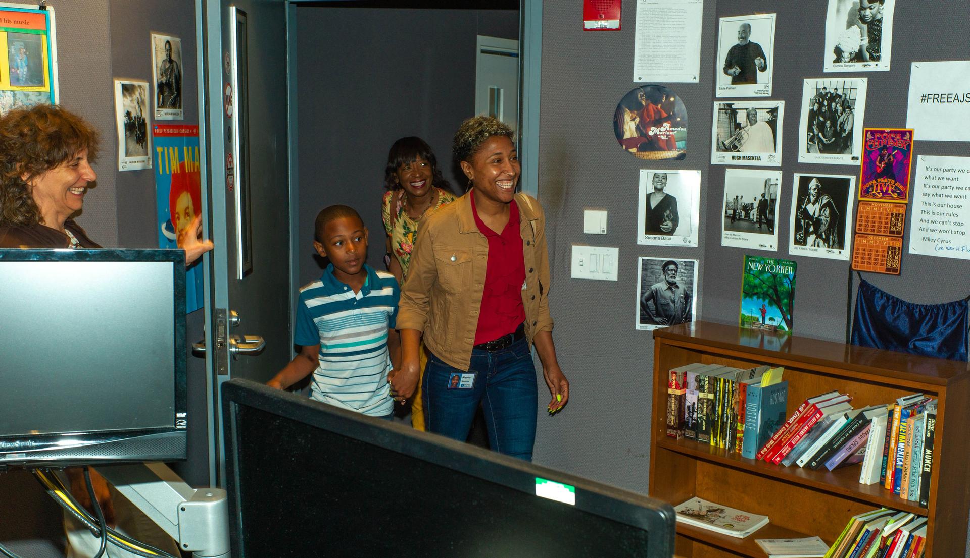 A woman smiles as she walks through a door, with other family members behind her