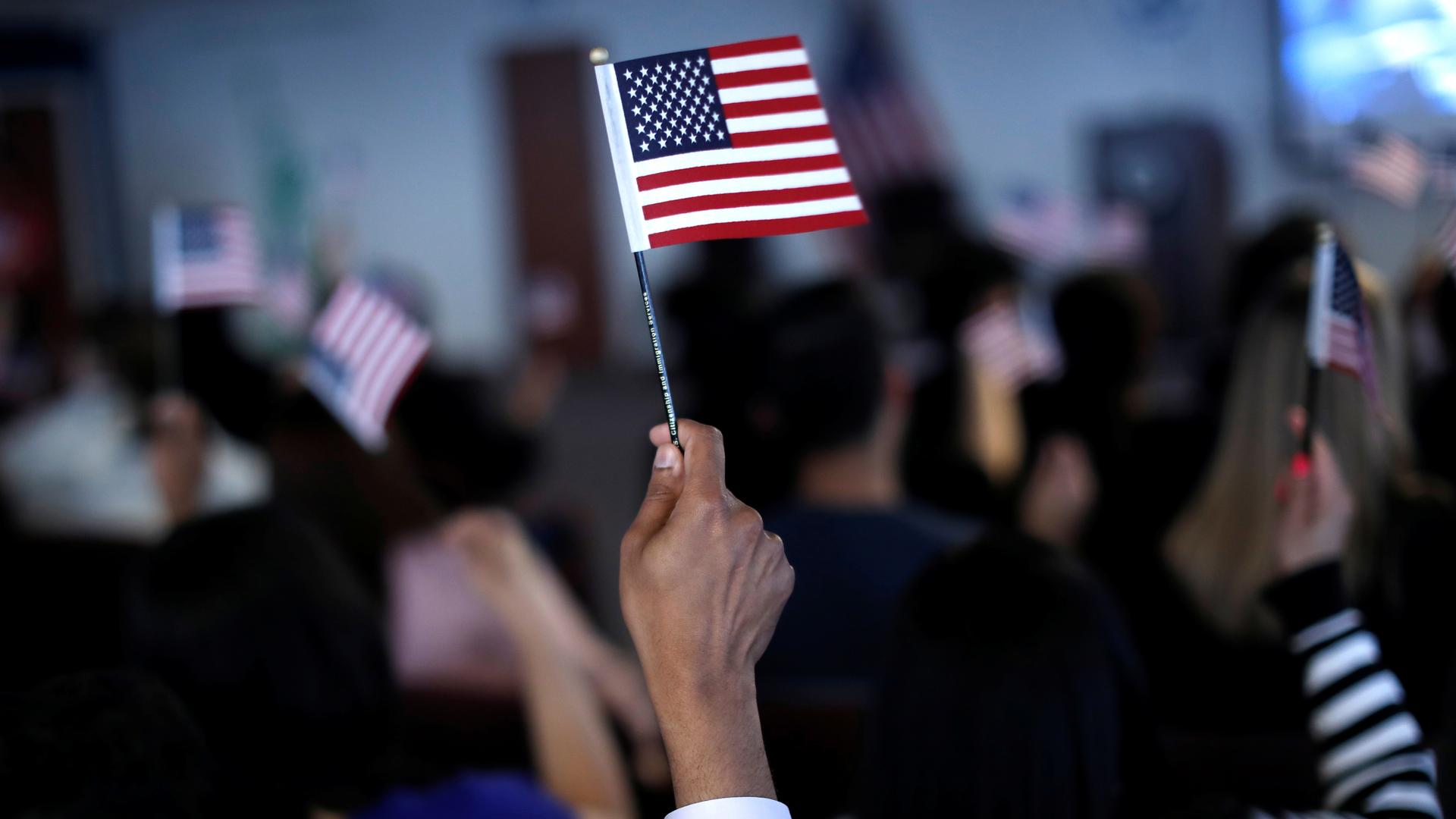 A hand waving a small American flag