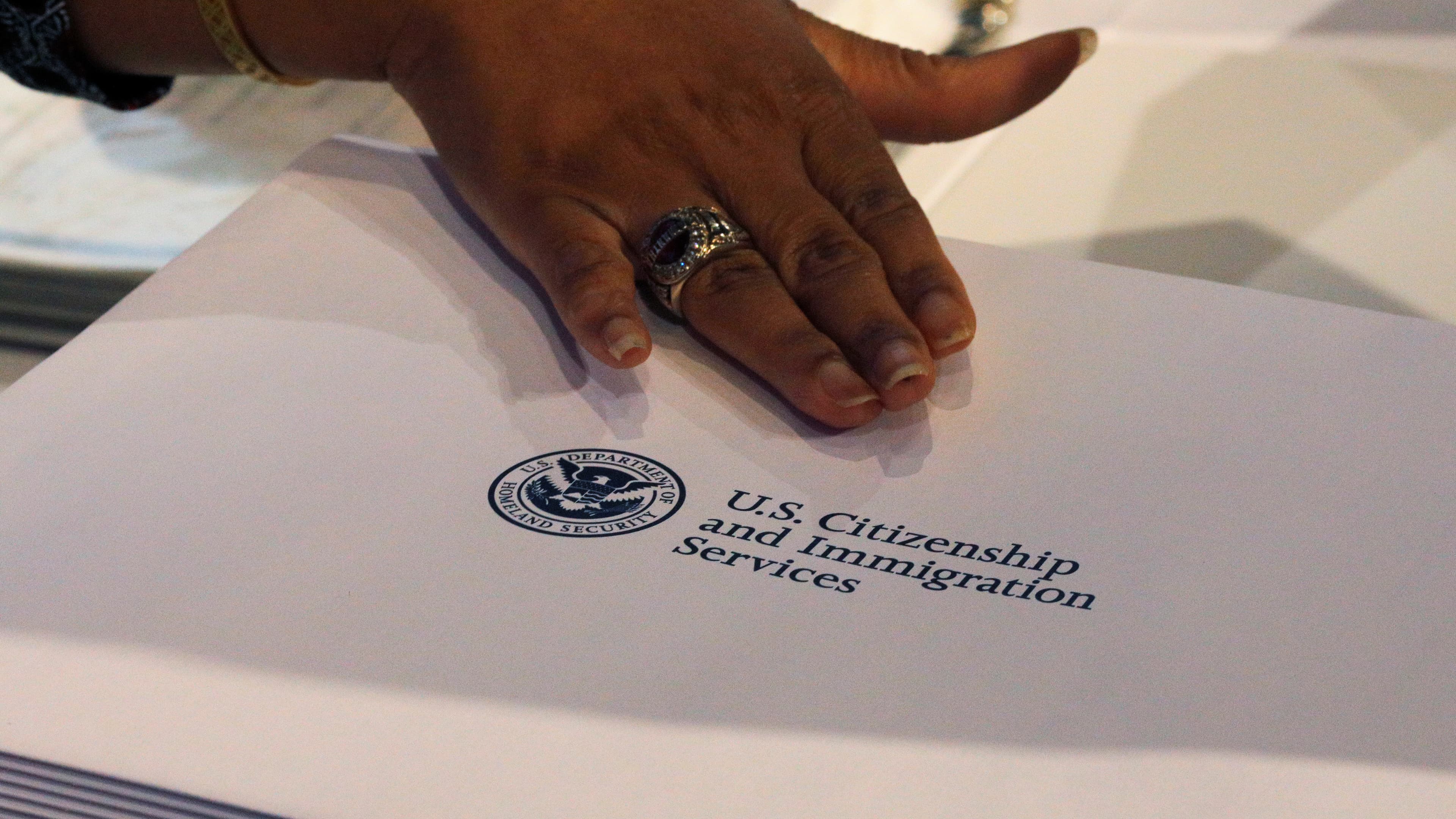 A close up of a hand and a USCIS folder