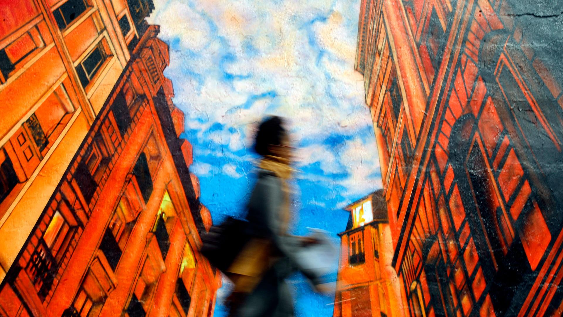 A woman walks by a mural in New York.
