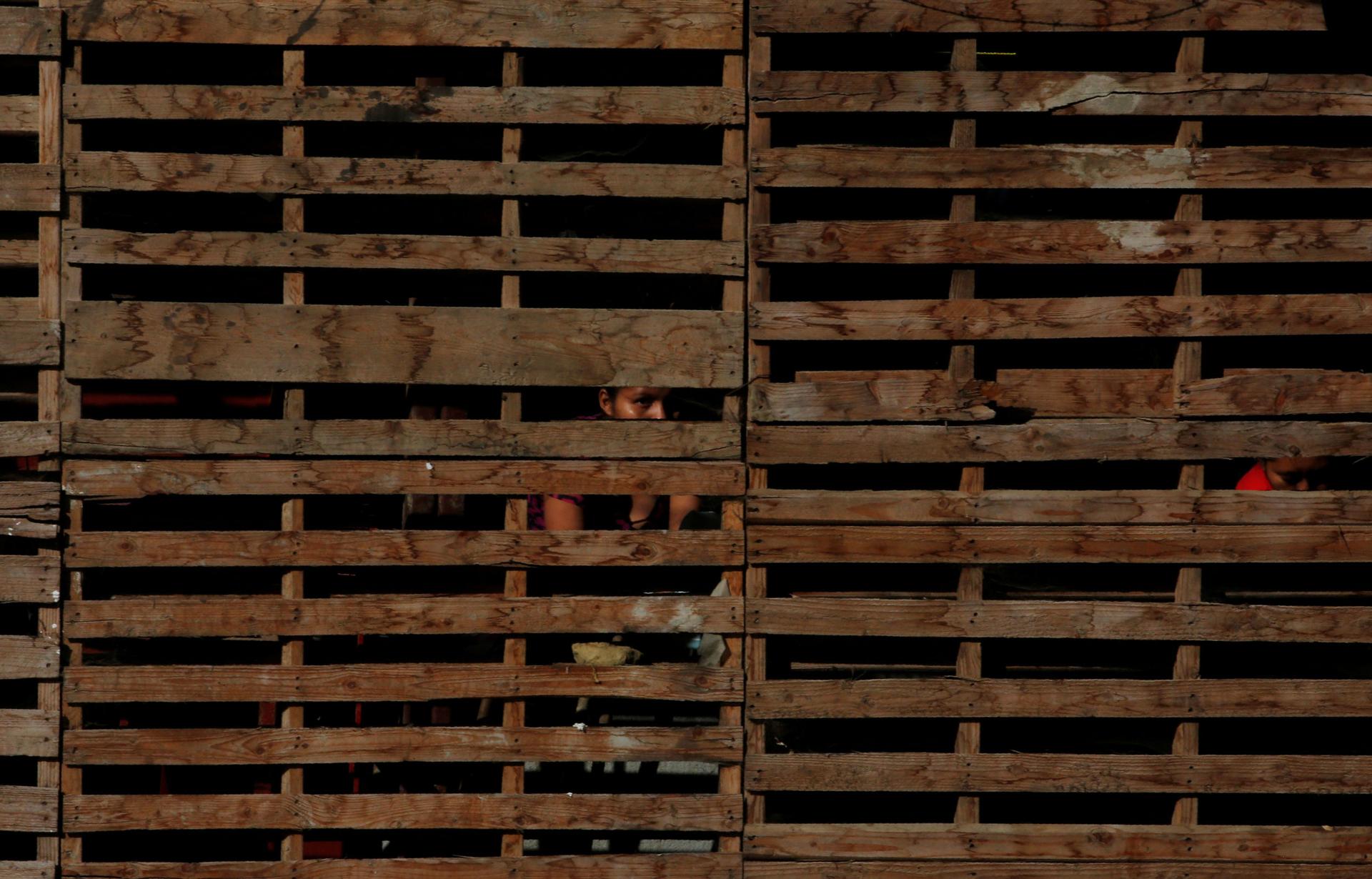 Horizontal wooden slats are shown across the entire photograph with the face of a woman in shadown.