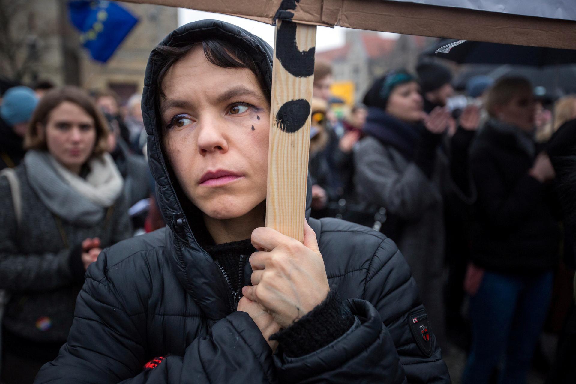A woman protests against abortion restrictions carrying sign with tear drops painted on her face