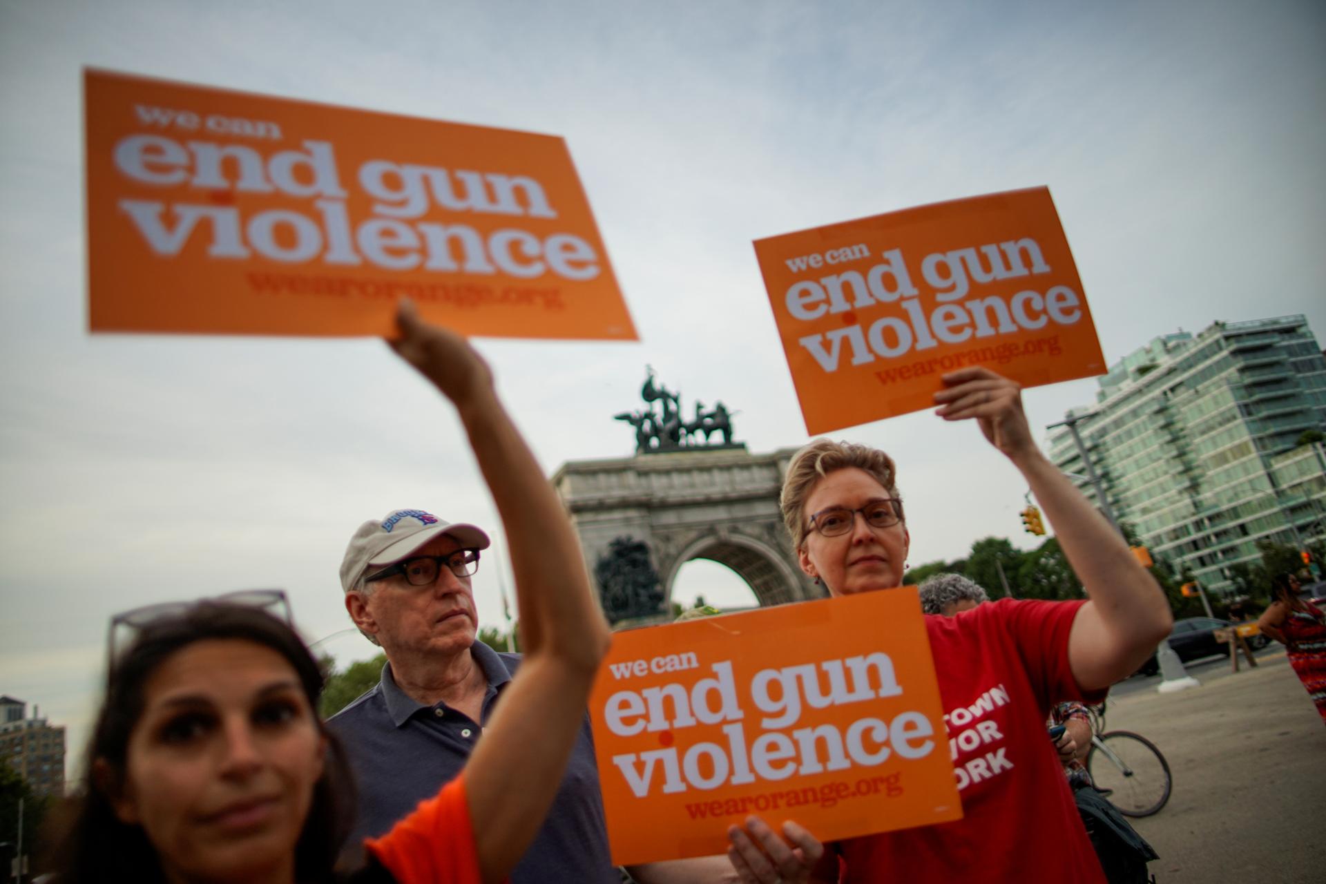 Protesters hold signs that say "We can end gun violence." 