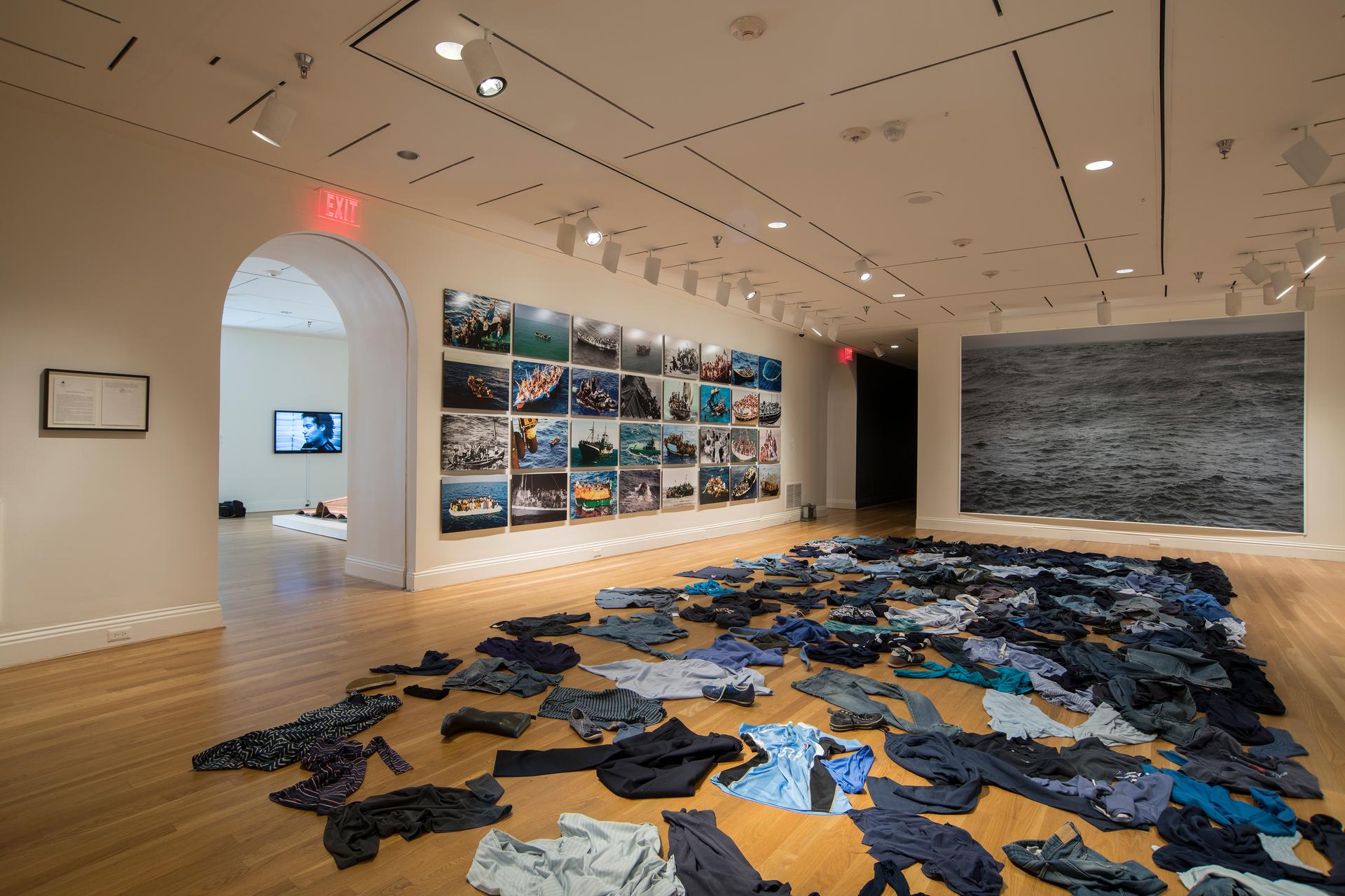 Dark colored clothes are strewn on the floor in an art exhibition.
