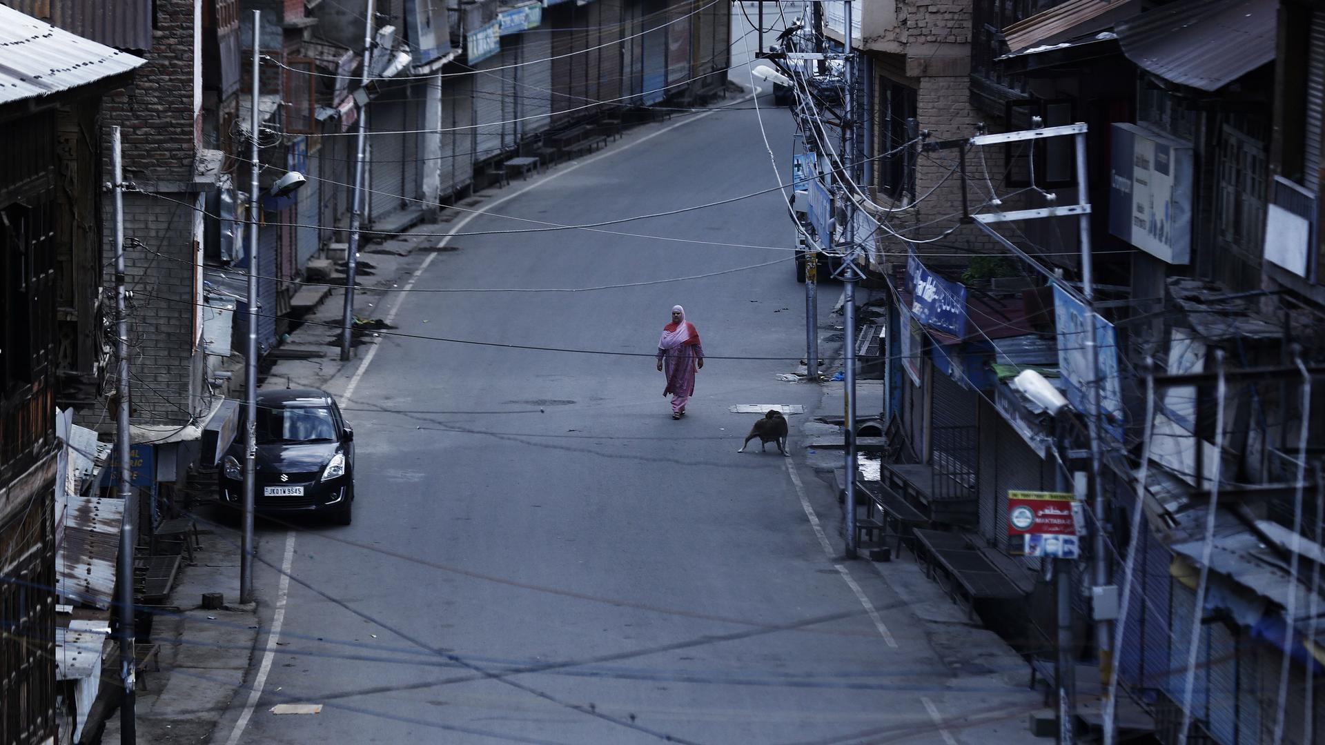 A Kashmiri woman walks on a deserted road in Srinagar.