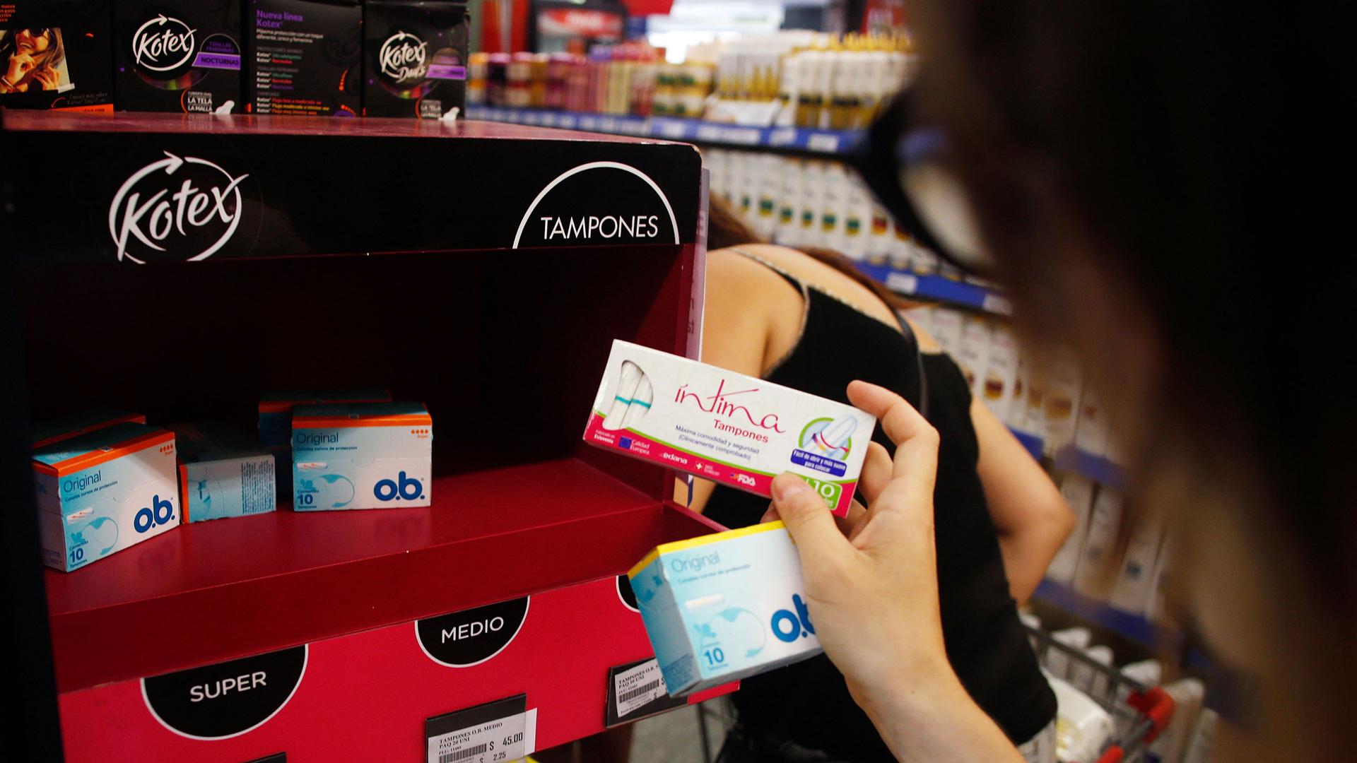 A woman takes tampon boxes out of a supermarket shelf in Buenos Aires January 16, 2015.  