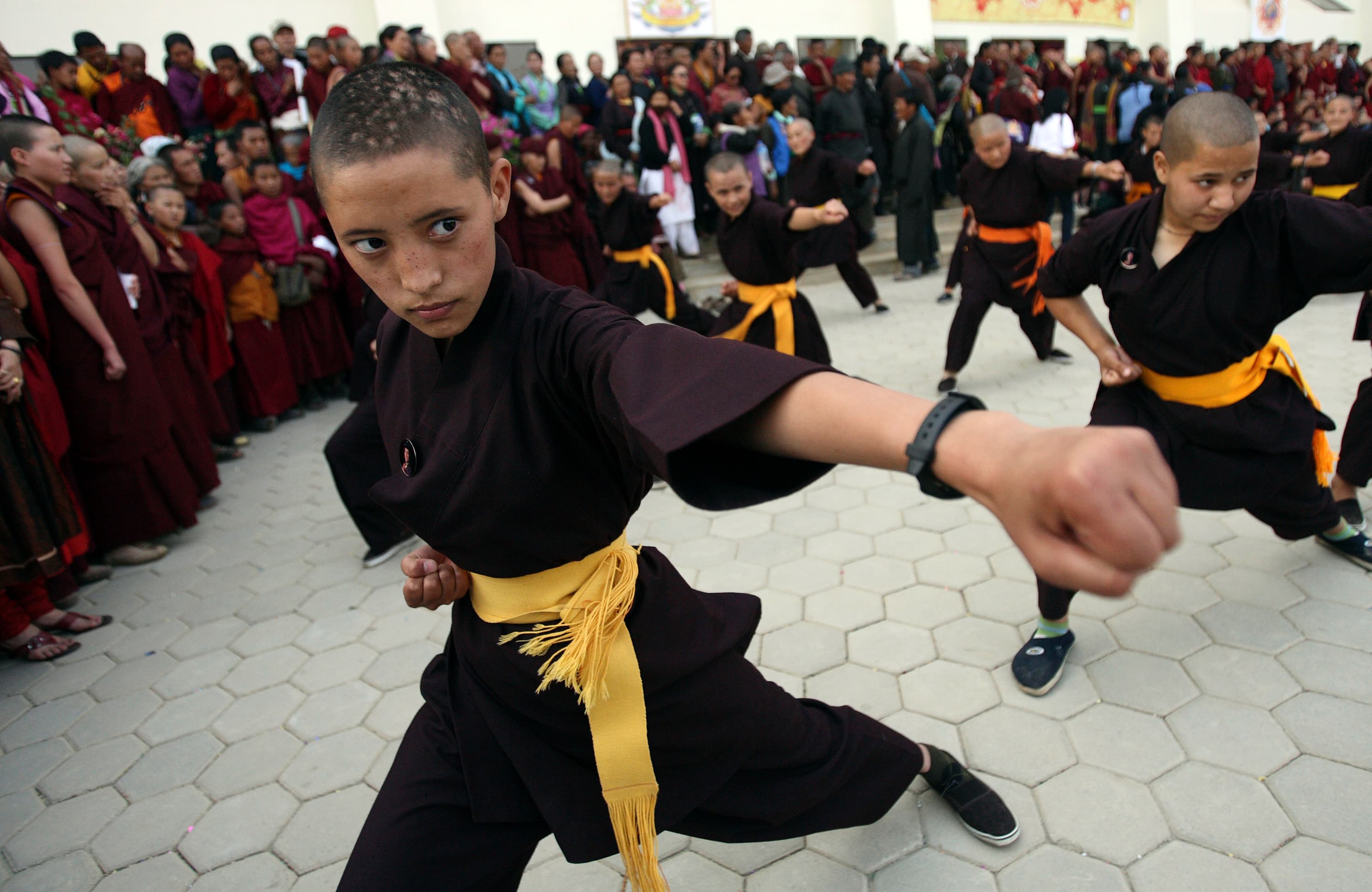 A Buddhist nun with a shaved head takes part in a Kung Fu display