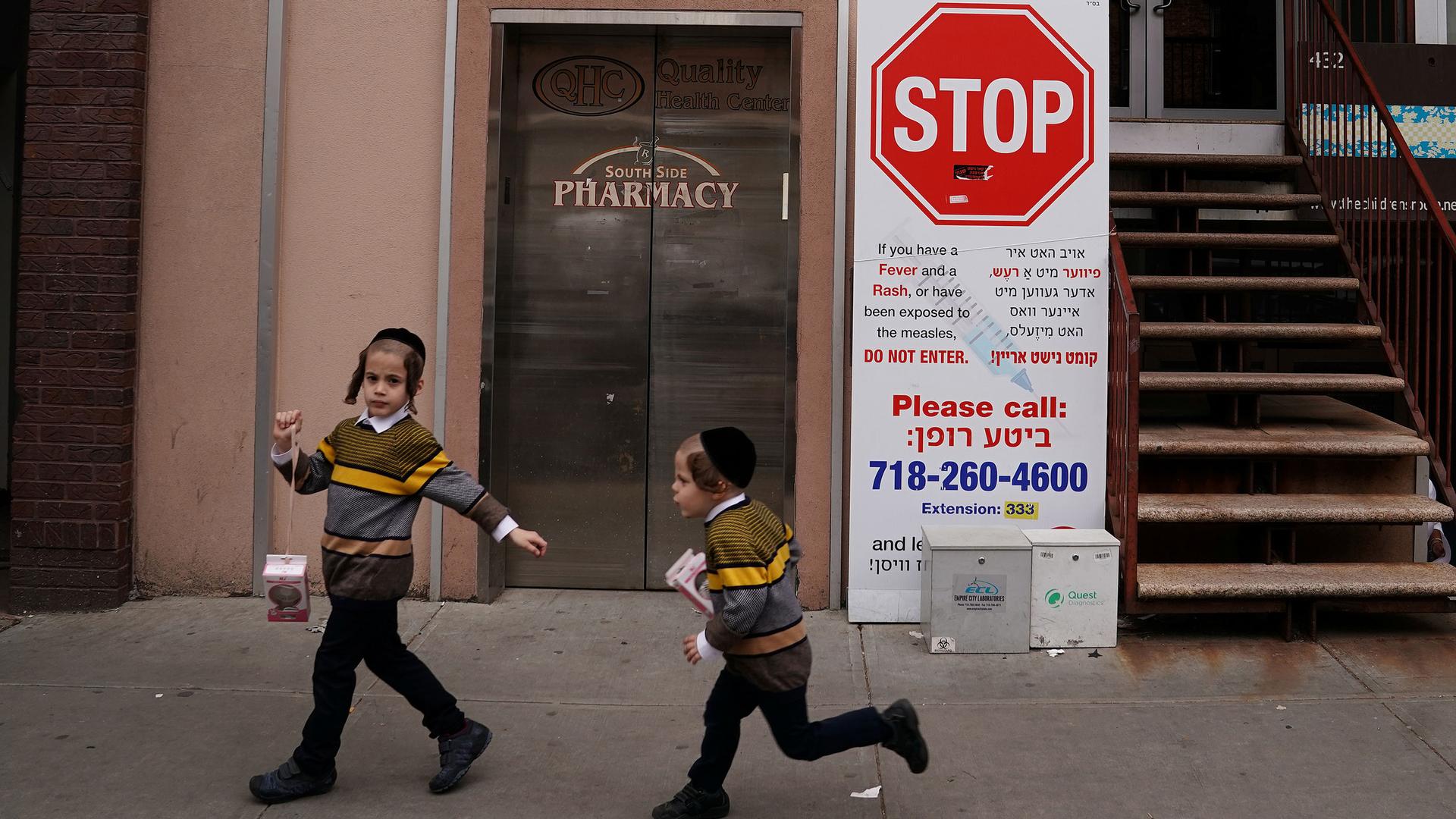 Two children are shown wearing matching stripped sweaters and running past a poster featuring a large stop sign.