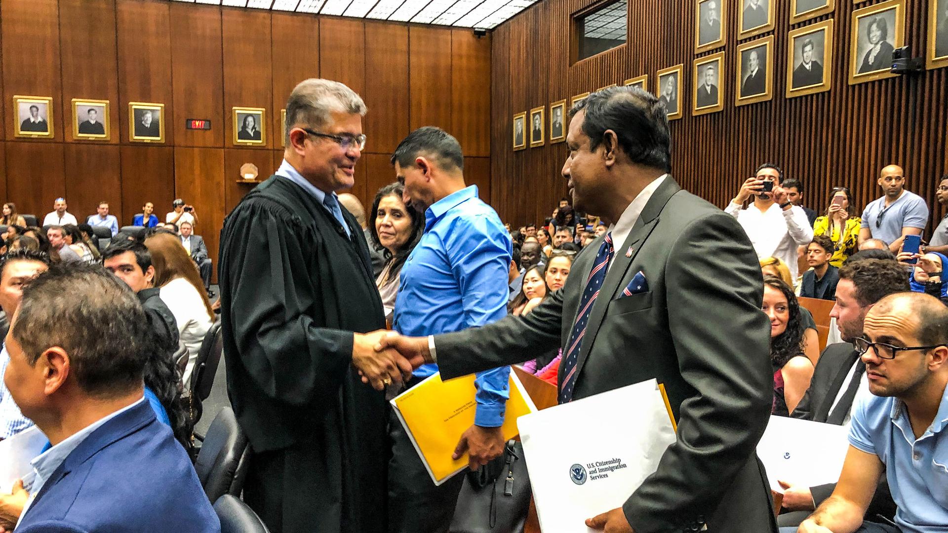 A judge shakes hands with a man at his citizenship ceremony