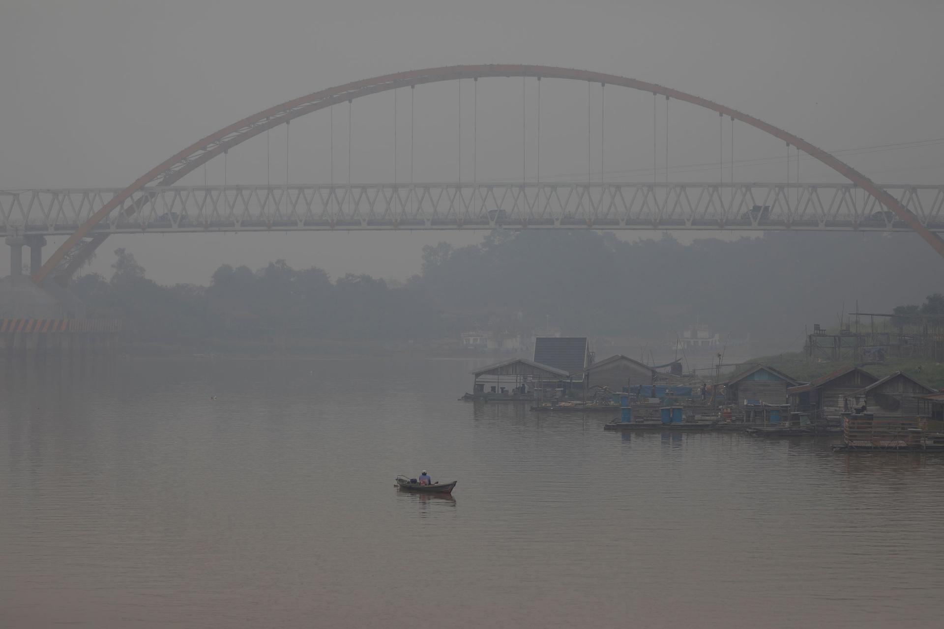 A small boat is shown with a suspension bridge in the background and the entire area shrowded in smoke.