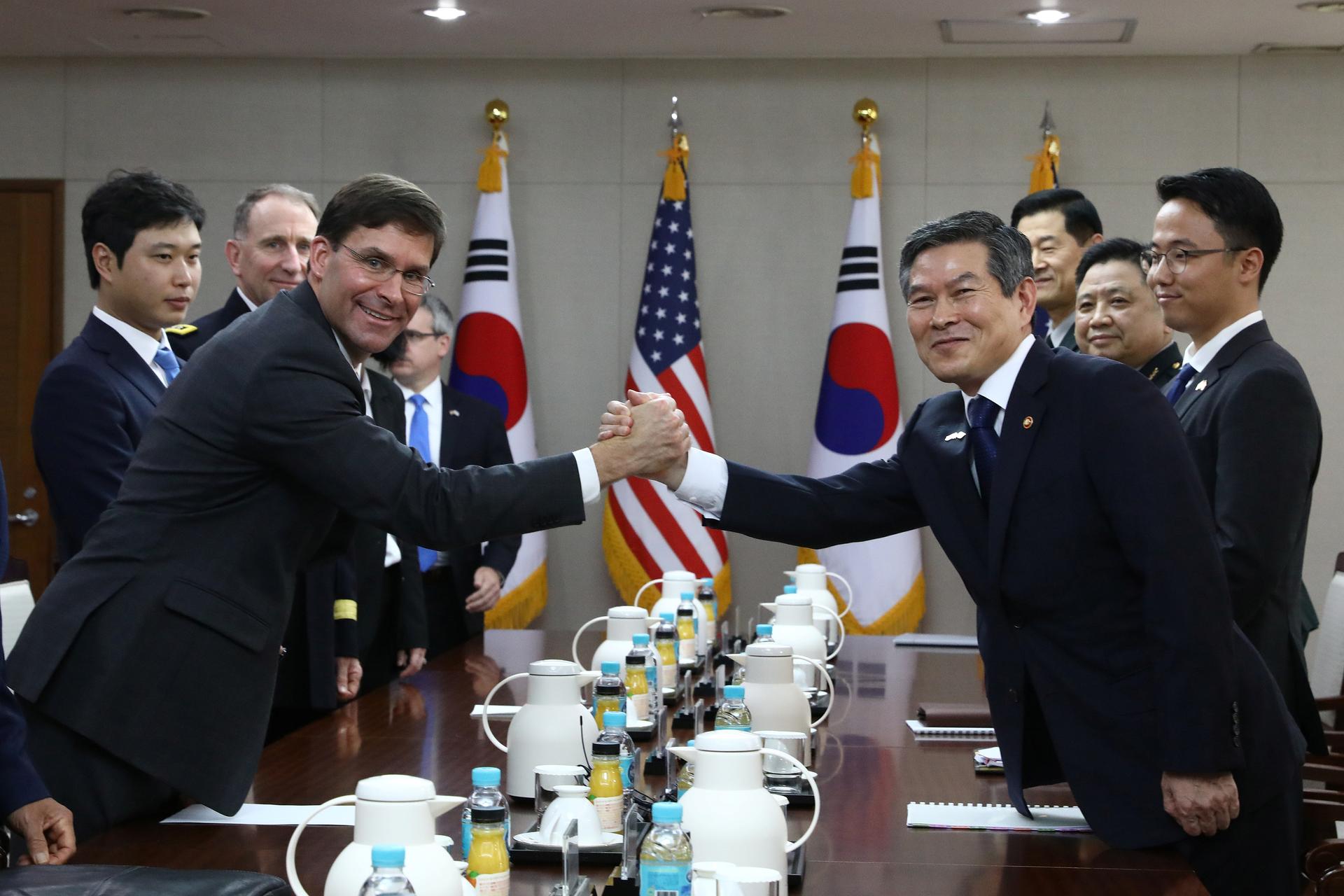 President Moon Jae-in shakes hands with US military wearing uniforms across a table