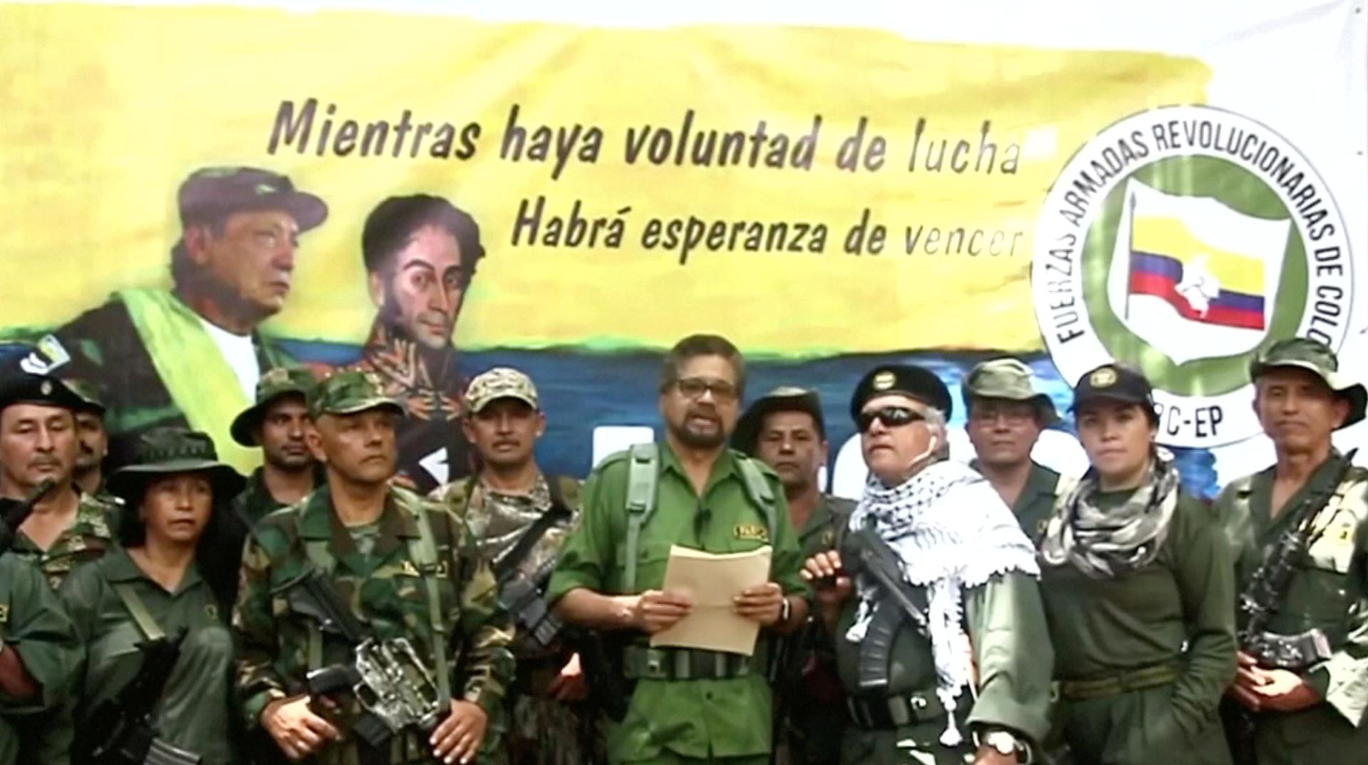 A group of FARC soldiers stand together reading from a paper. 