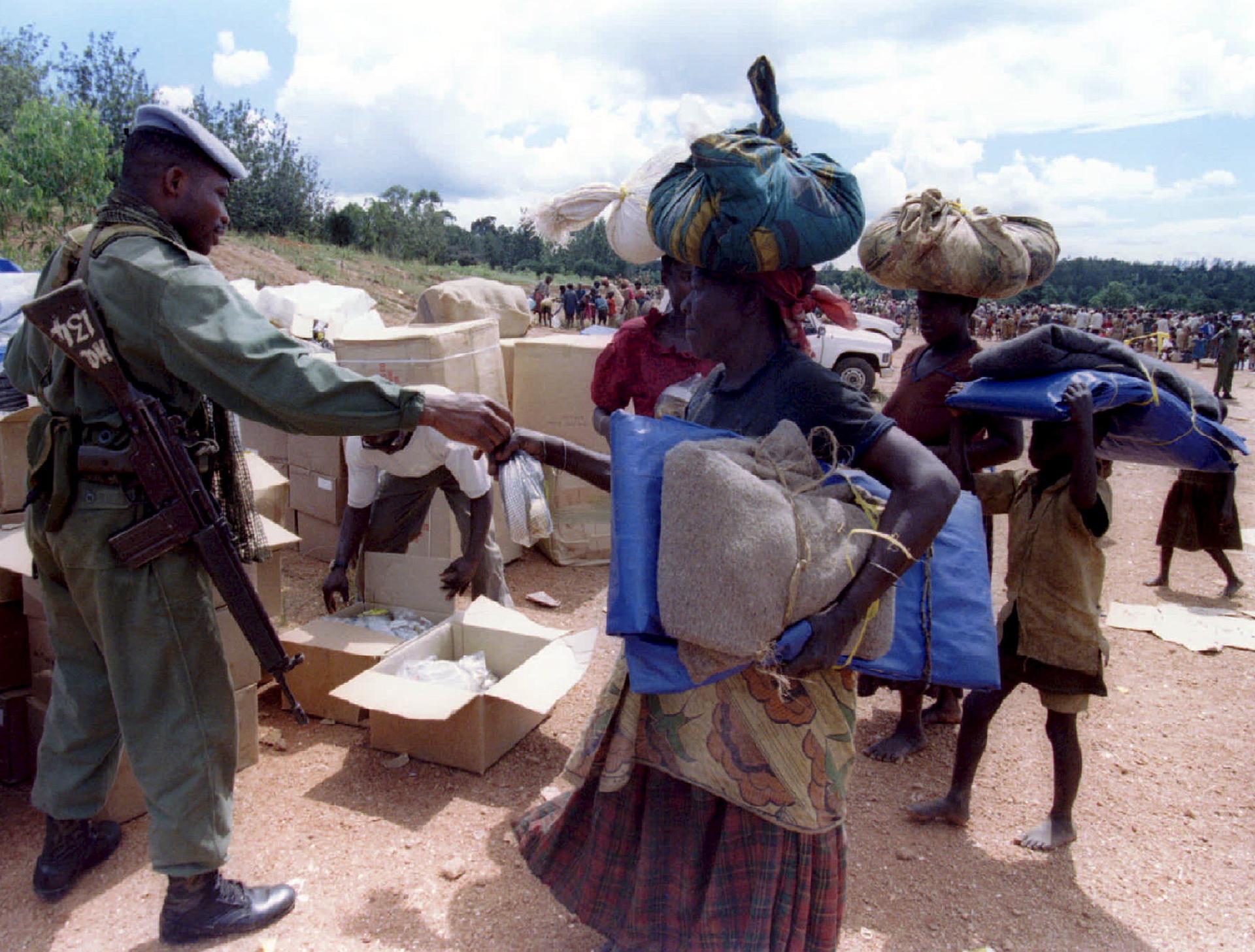A soldier hands food to a woman. 