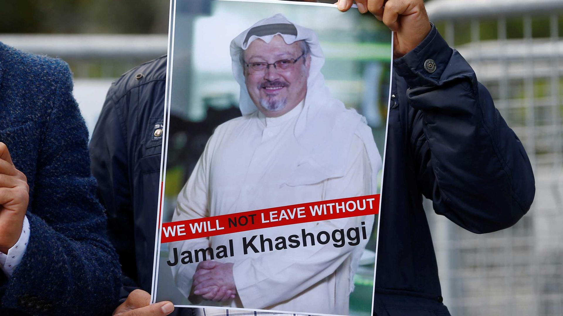 A man holds a sign that says "we will not leave without Jamal Khashoggi"