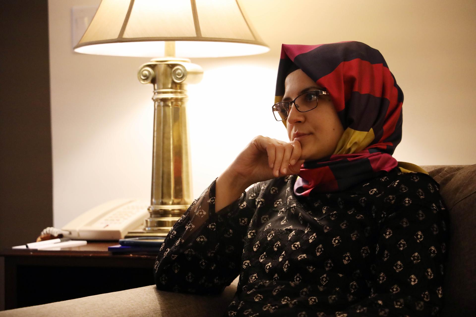 A woman in a headscarf sits on a couch