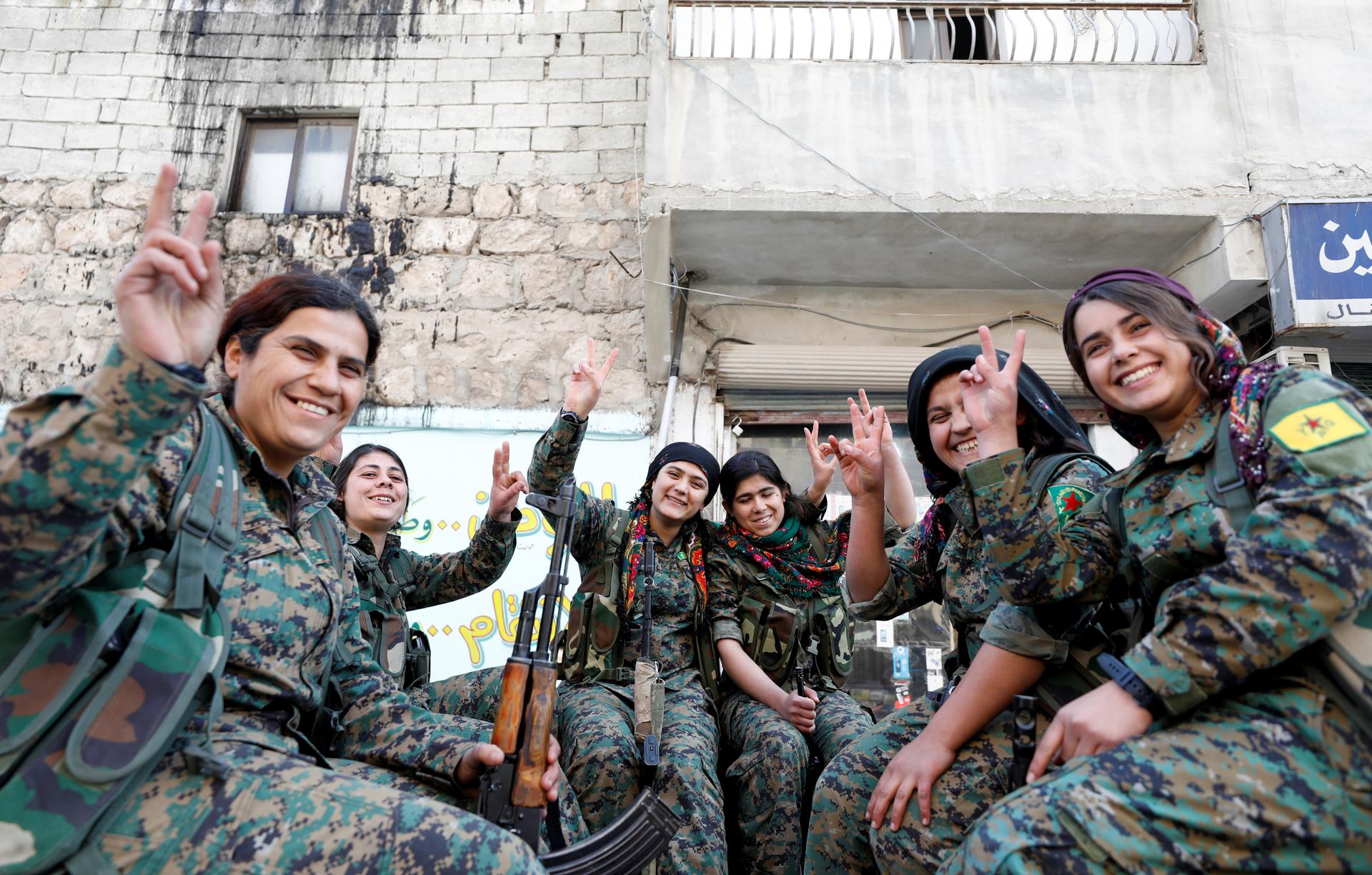 A semicircle of Kurdish female fighters of the Women's Protection Unit (YPJ) gesturing V for Victory symbols in the Sheikh Maksoud neighbourhood of Aleppo, Syria, on Feb. 7, 2018.