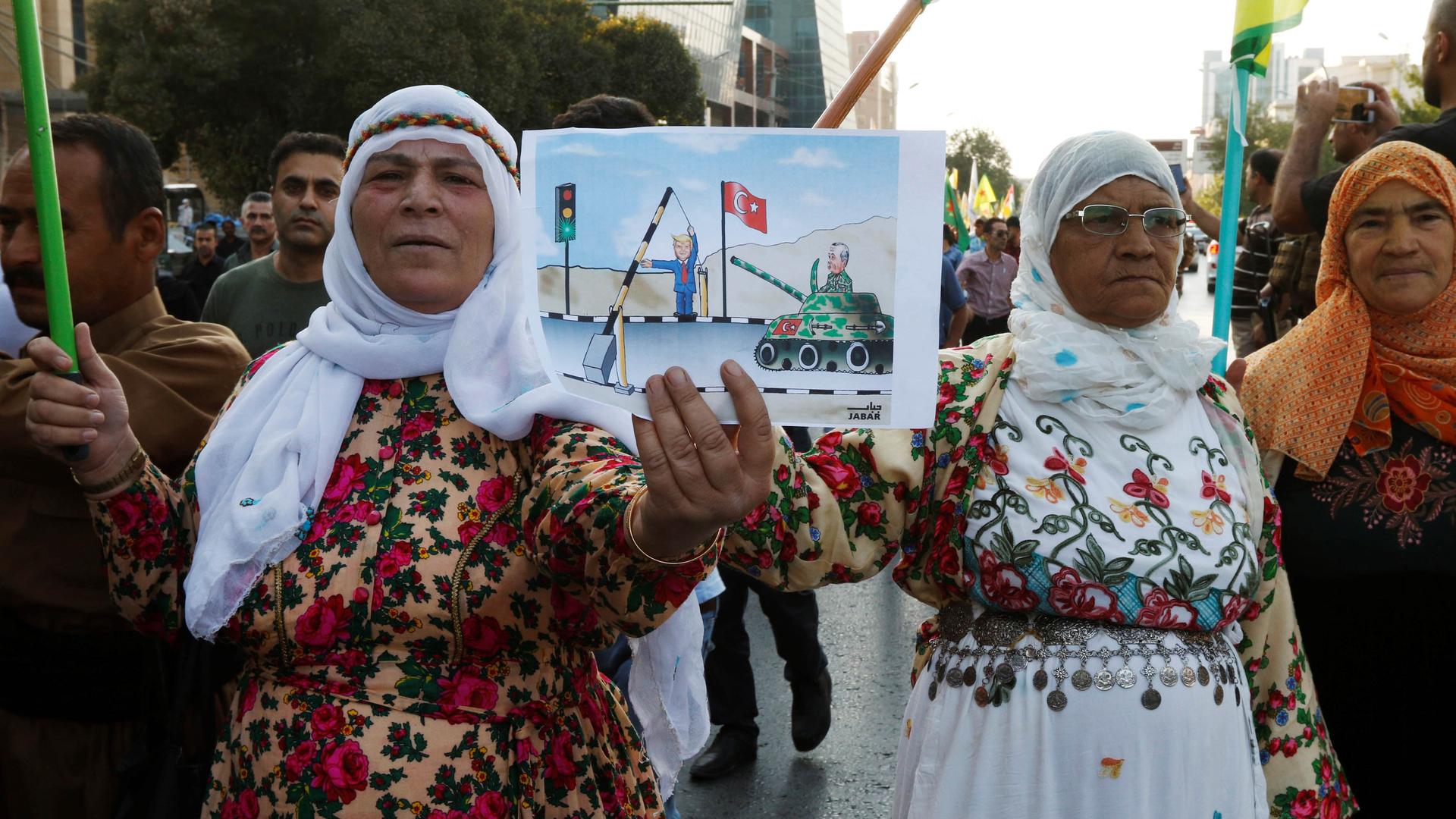 Older women hold a cartoon graphic depicting Donald Trump and a Turkish tank. 