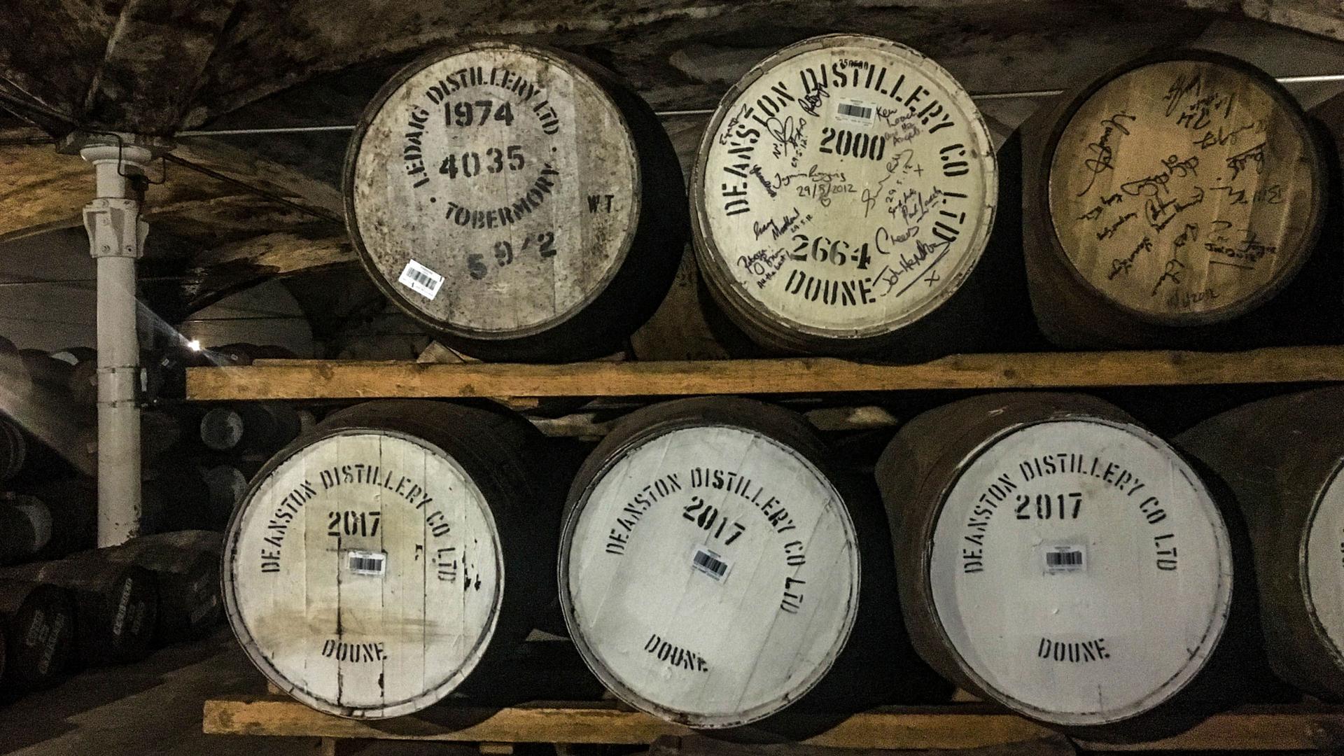 Wooden barrels of Scotch sit on a shelf in a storage area