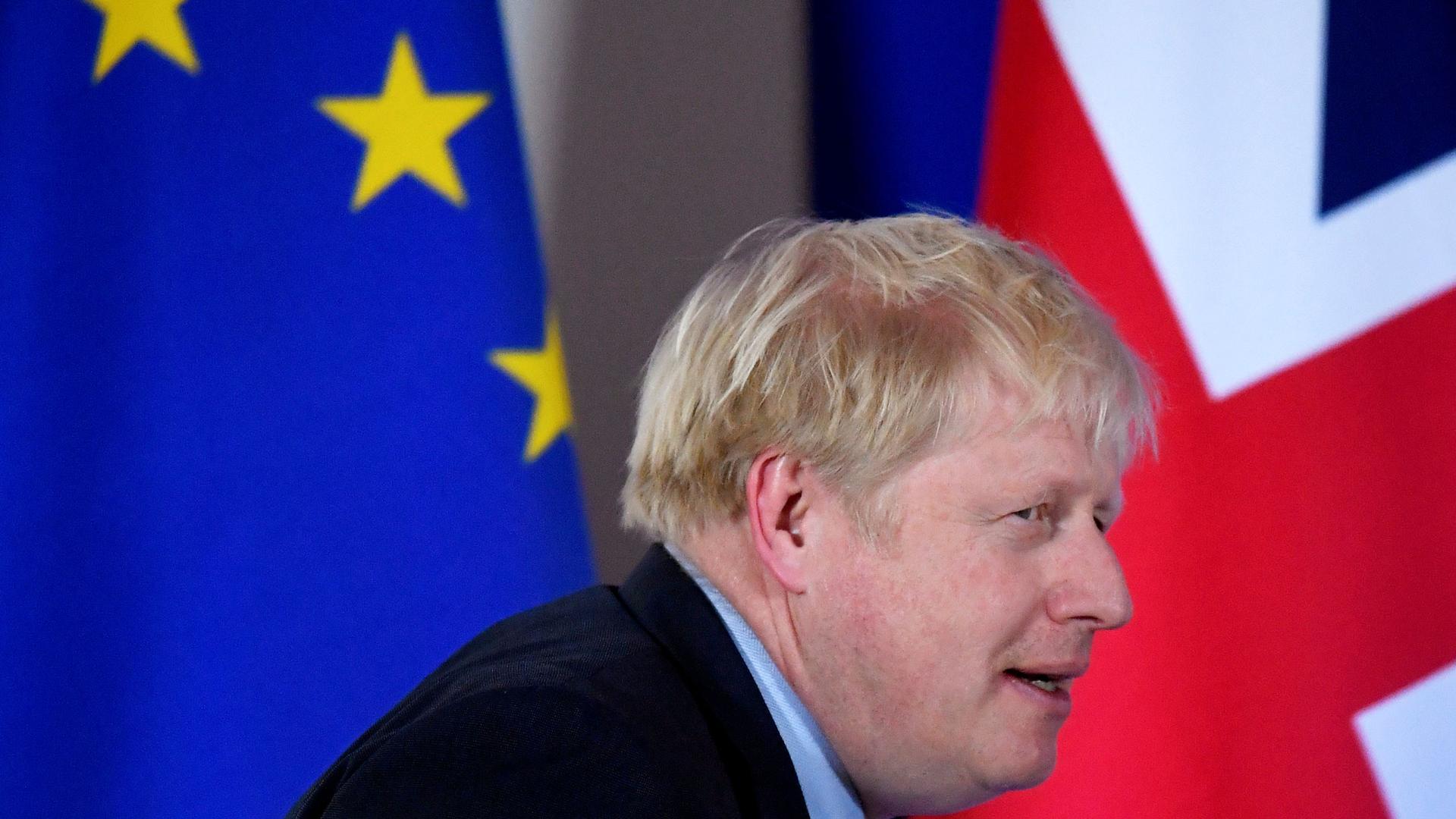 Britain's Prime Minister Boris Johnson is shown walking past the EU and UK flags.