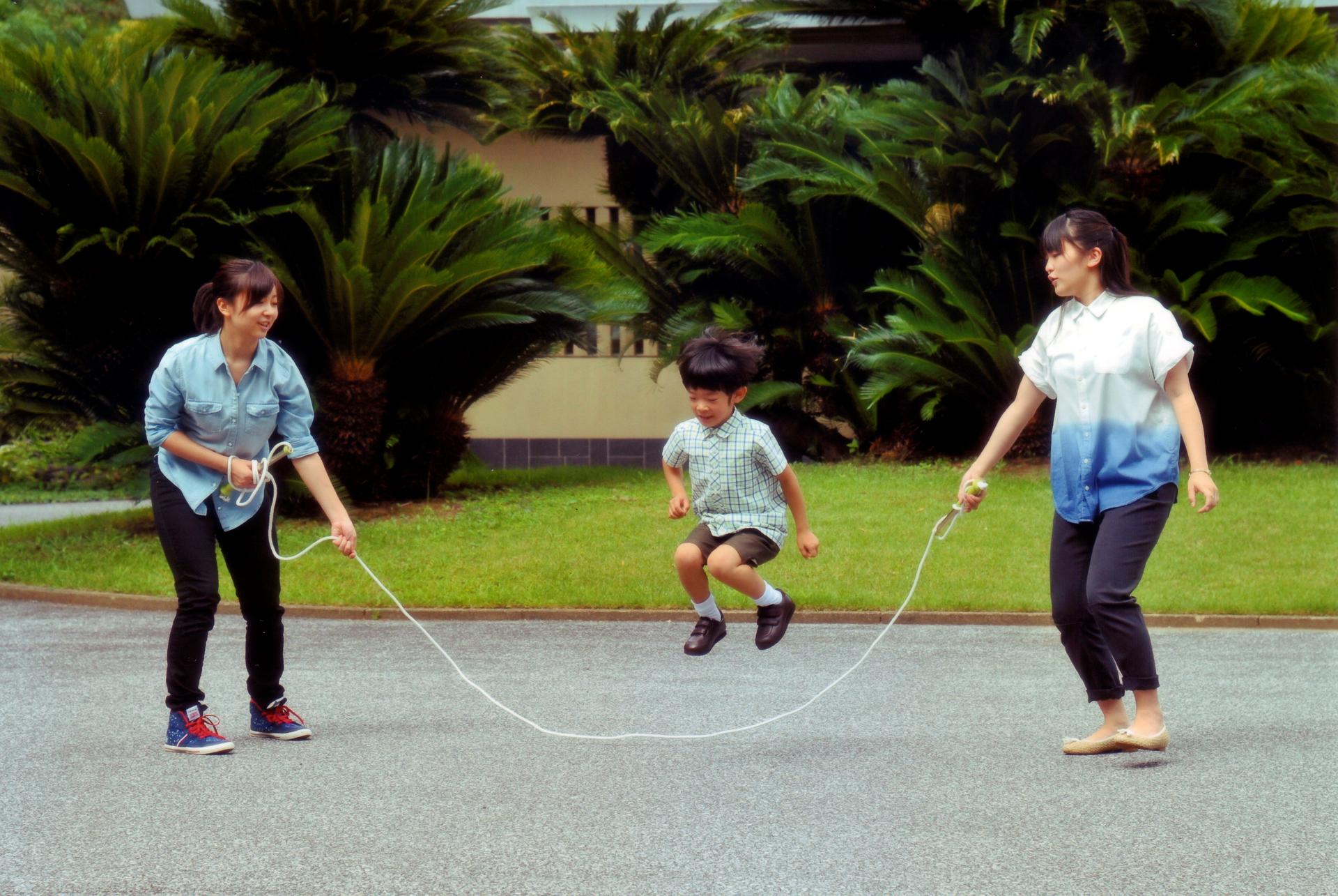 A young boy jumps rope that two young girls are swinging