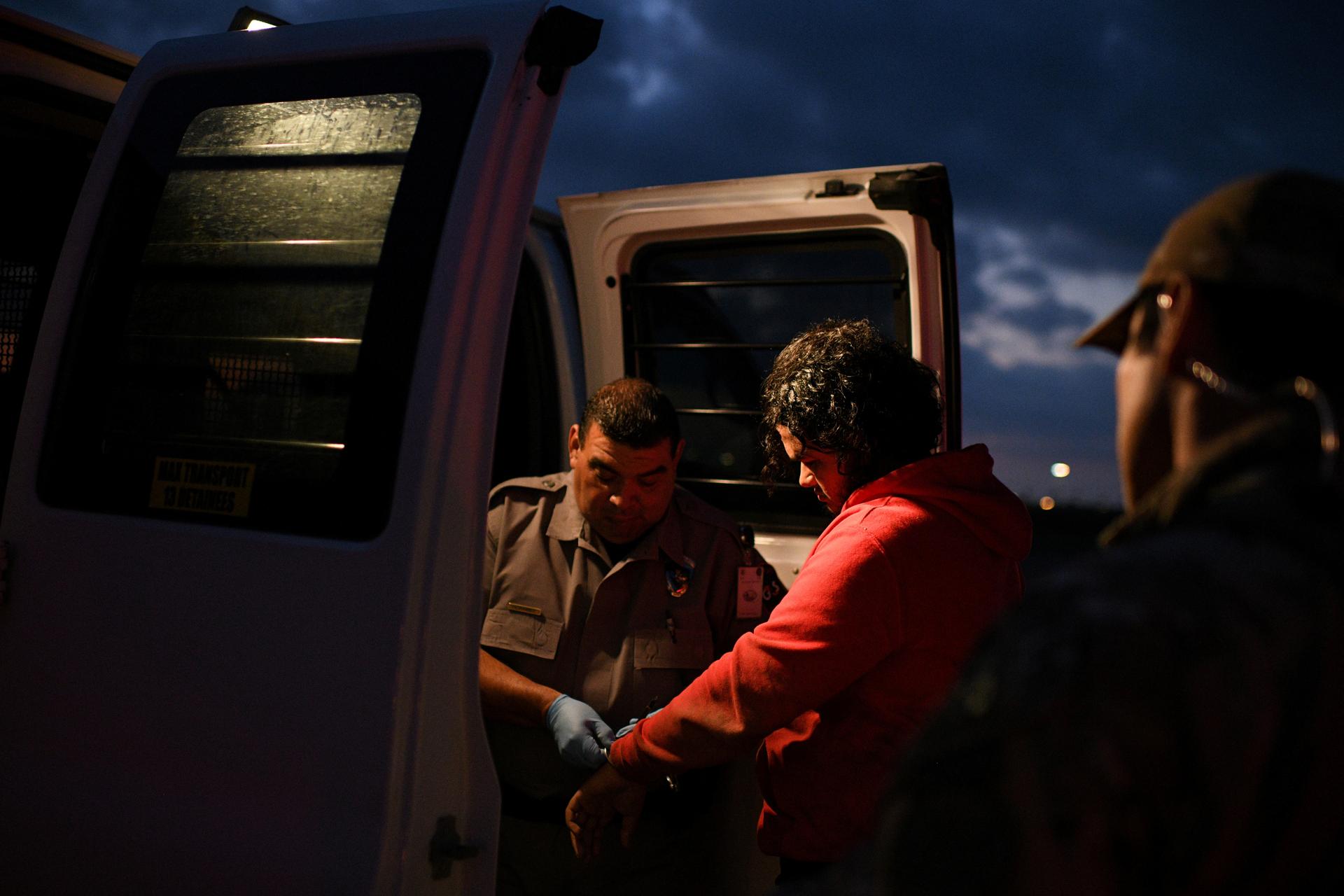 Undocumented migrants are escorted into a transport van after being apprehended by US Border Patrol agents following an illegal crossing of the Rio Grande in Mission, Texas, on Oct. 8, 2019.