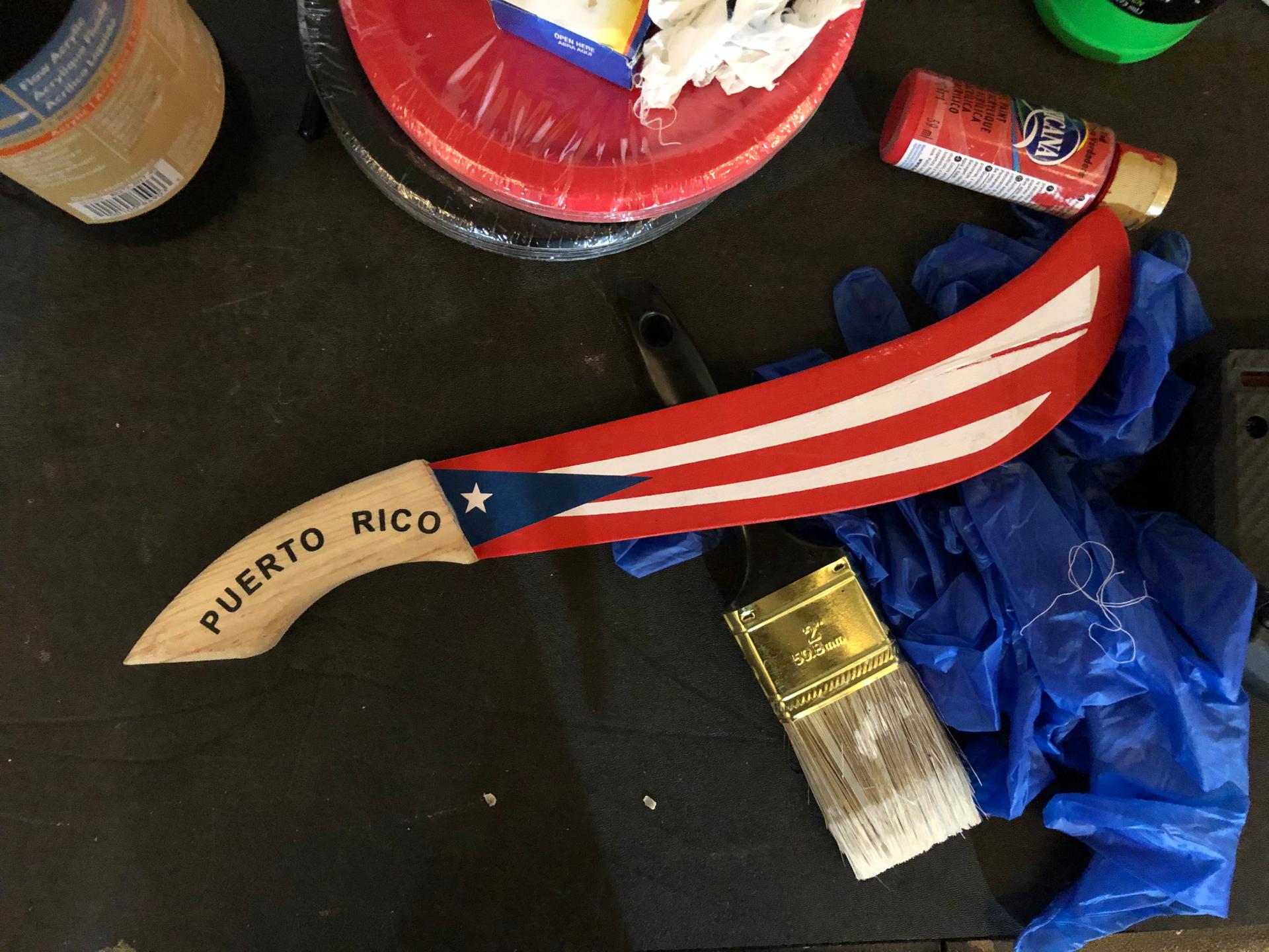 A prop wooden machete painted red, white and blue to match the Puerto Rican flag.
