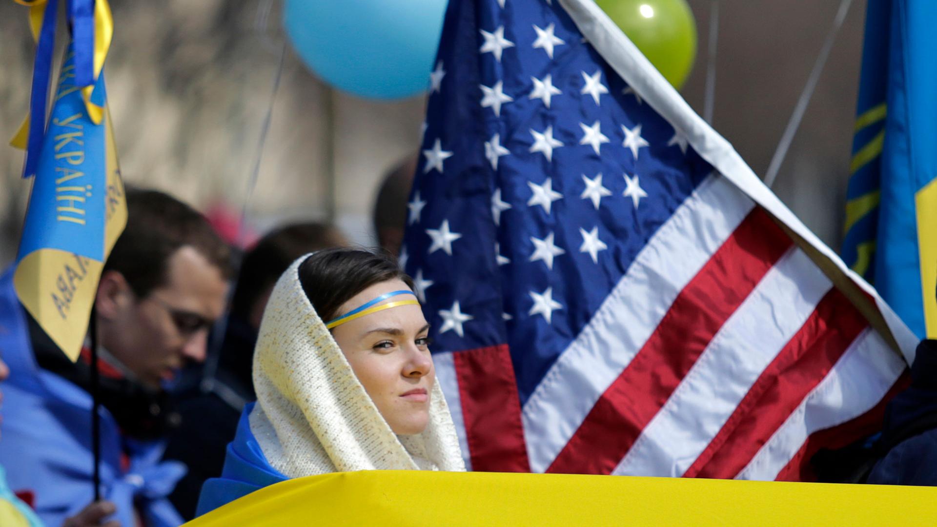 A woman surrounded by US and Ukrainian flags