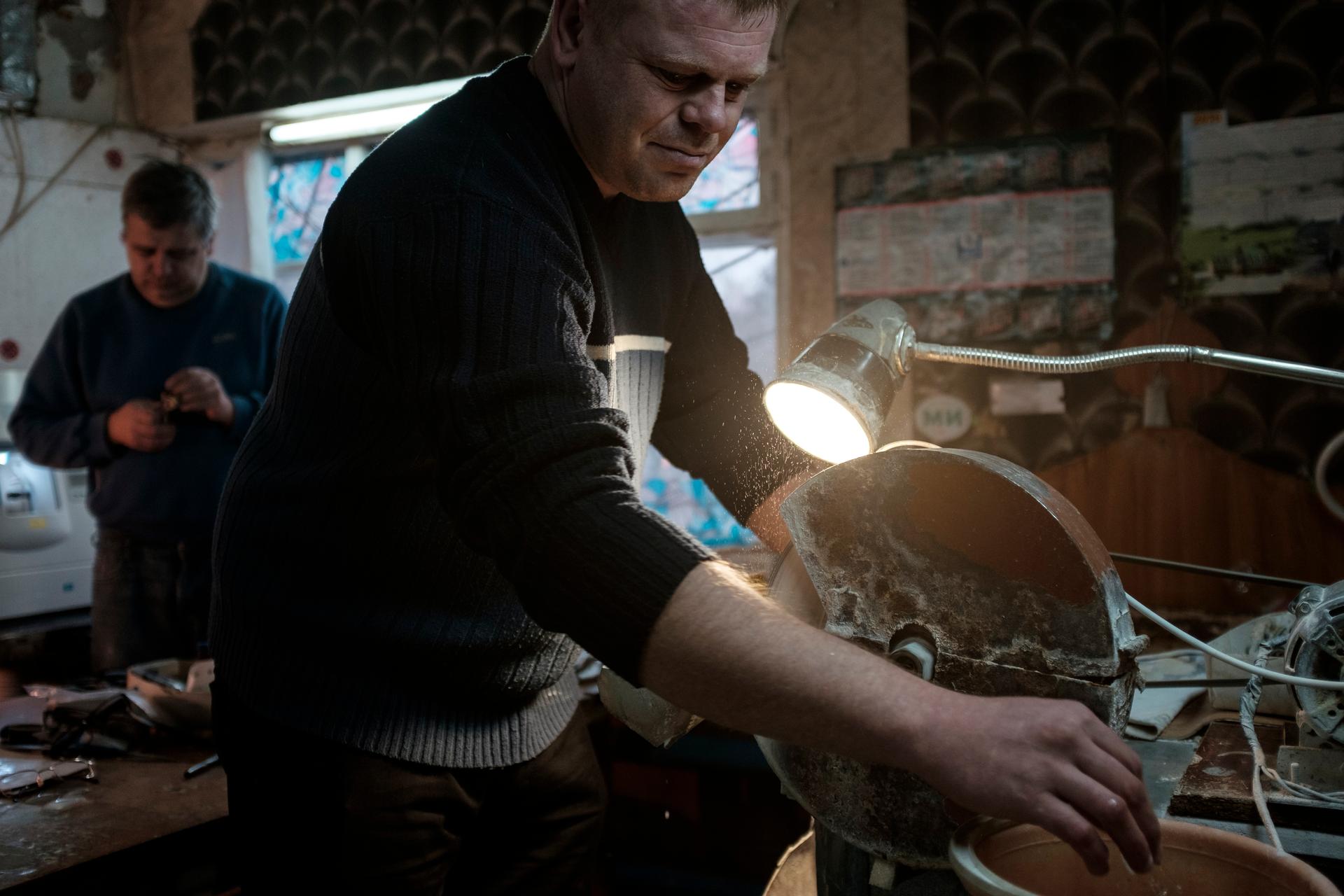 A man in shadow works at a grinder